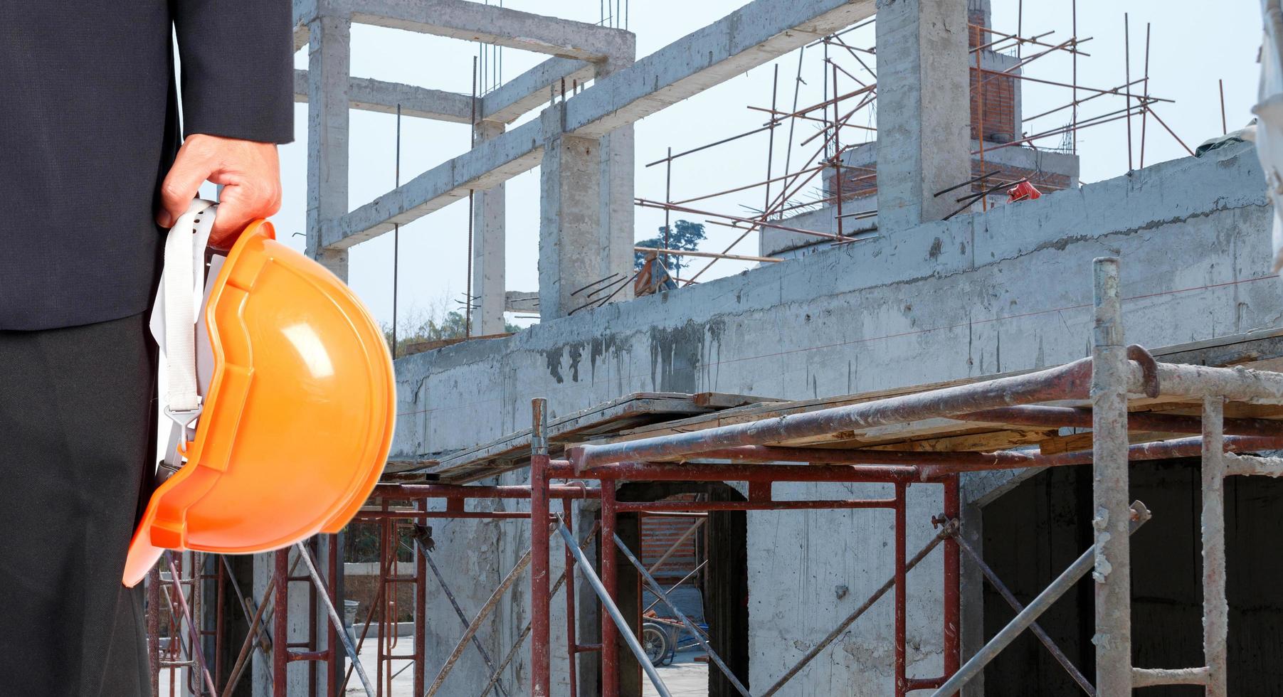 ingegnere che tiene un cappello di sicurezza arancione sullo sfondo del cantiere foto