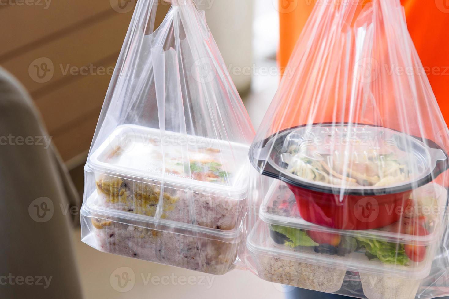 scatole di cibo asiatico in sacchetti di plastica consegnate al cliente a casa dal fattorino foto