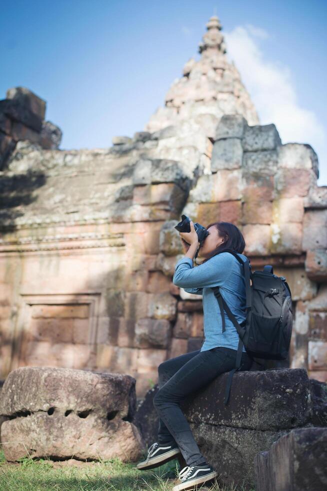 giovane turista attraente del fotografo con lo zaino che viene a scattare foto all'antico tempio di phanom rung in tailandia.