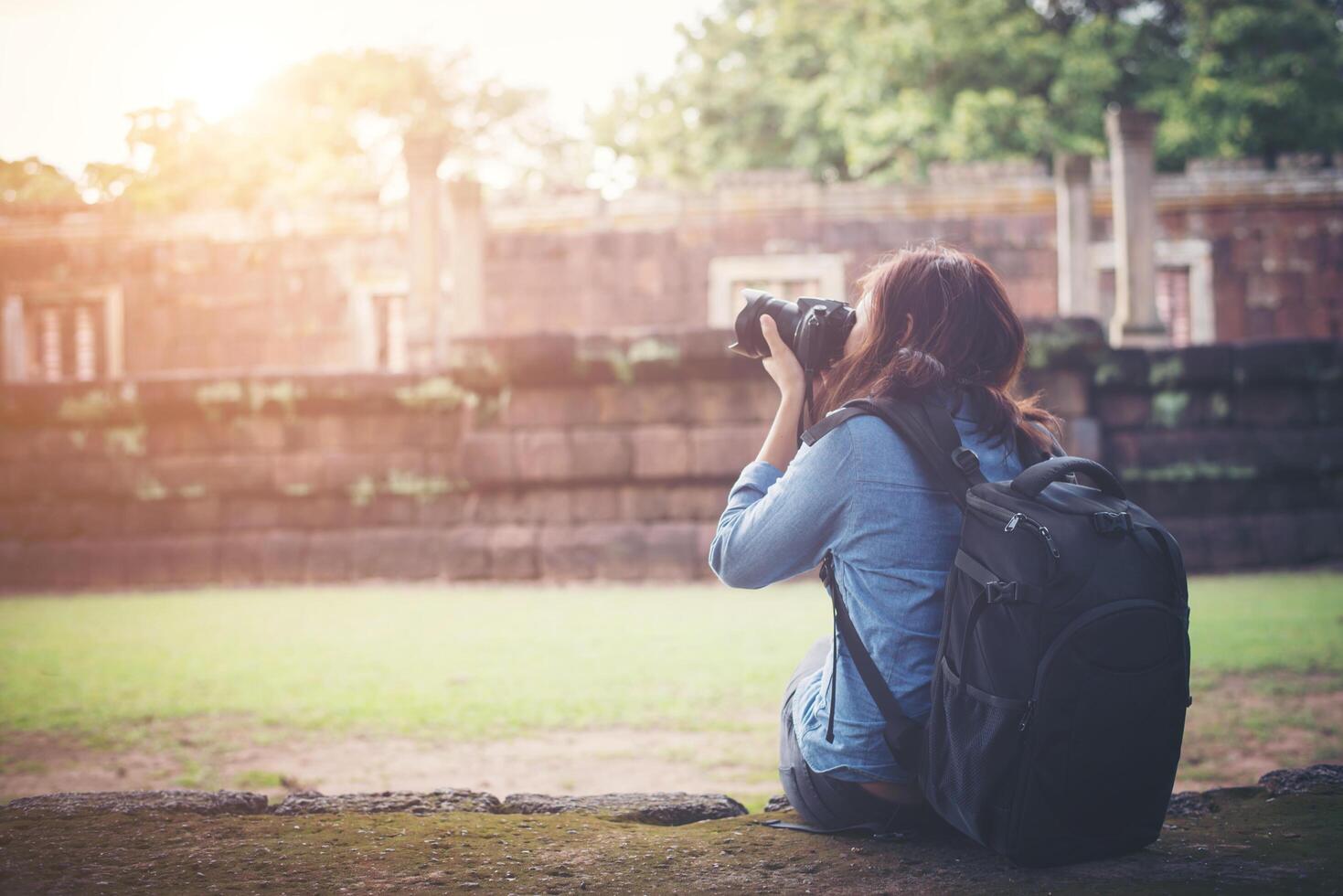 giovane turista attraente del fotografo con lo zaino che viene a scattare foto all'antico tempio di phanom rung in tailandia.