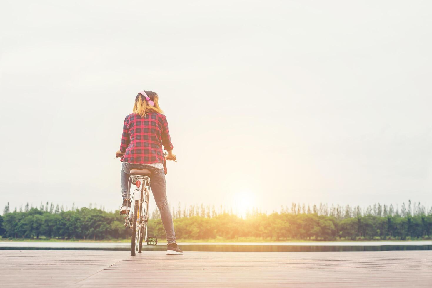 parte posteriore della giovane donna hipster in bicicletta con la bicicletta su un molo, rilassarsi godersi le vacanze estive. foto