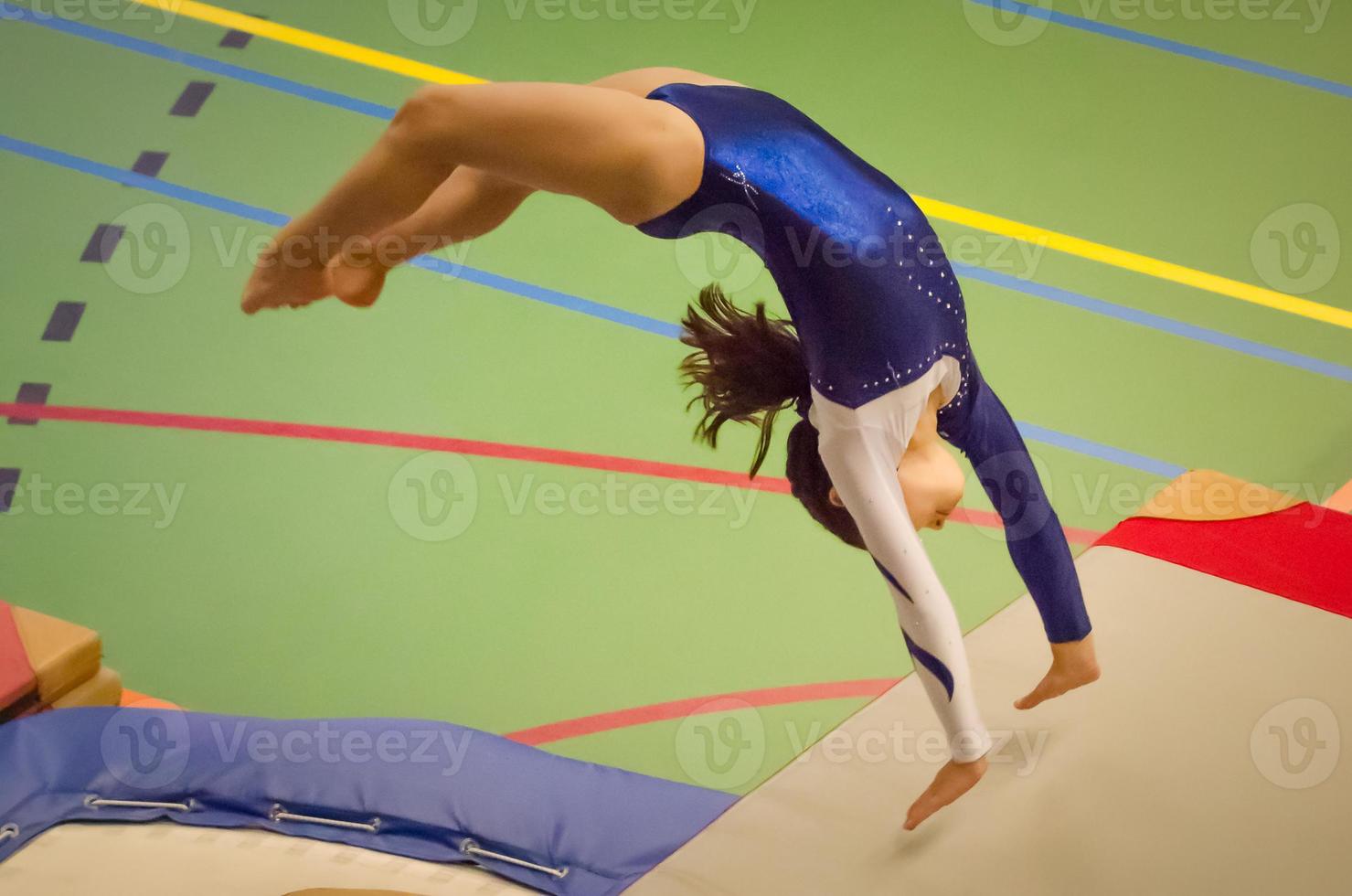 giovane ragazza ginnasta che esegue salto indietro handspring foto