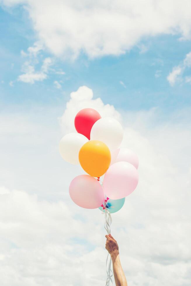 concetto di stile di vita donna donna mano che tiene un mazzo di palloncini colorati con cielo blu. foto