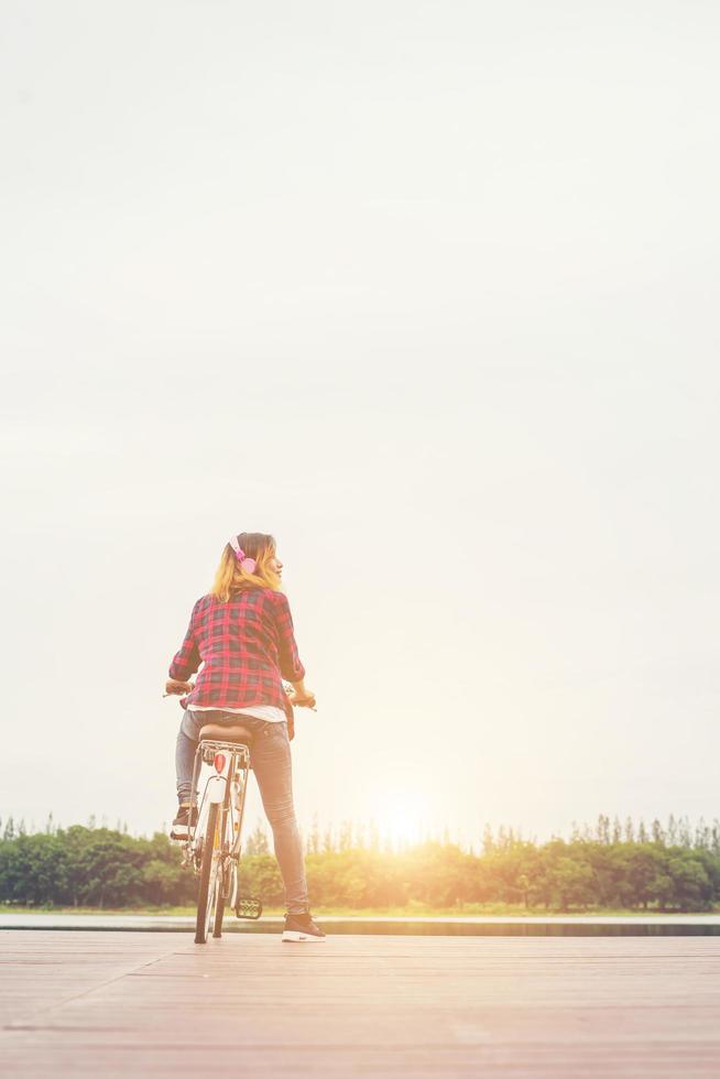 parte posteriore della giovane donna hipster in bicicletta con la bicicletta su un molo, rilassarsi godersi le vacanze estive. foto