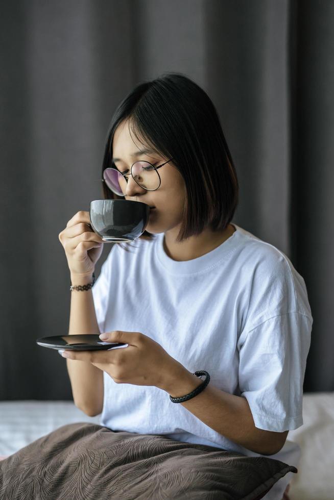 una ragazza seduta e bevendo caffè in camera da letto. foto