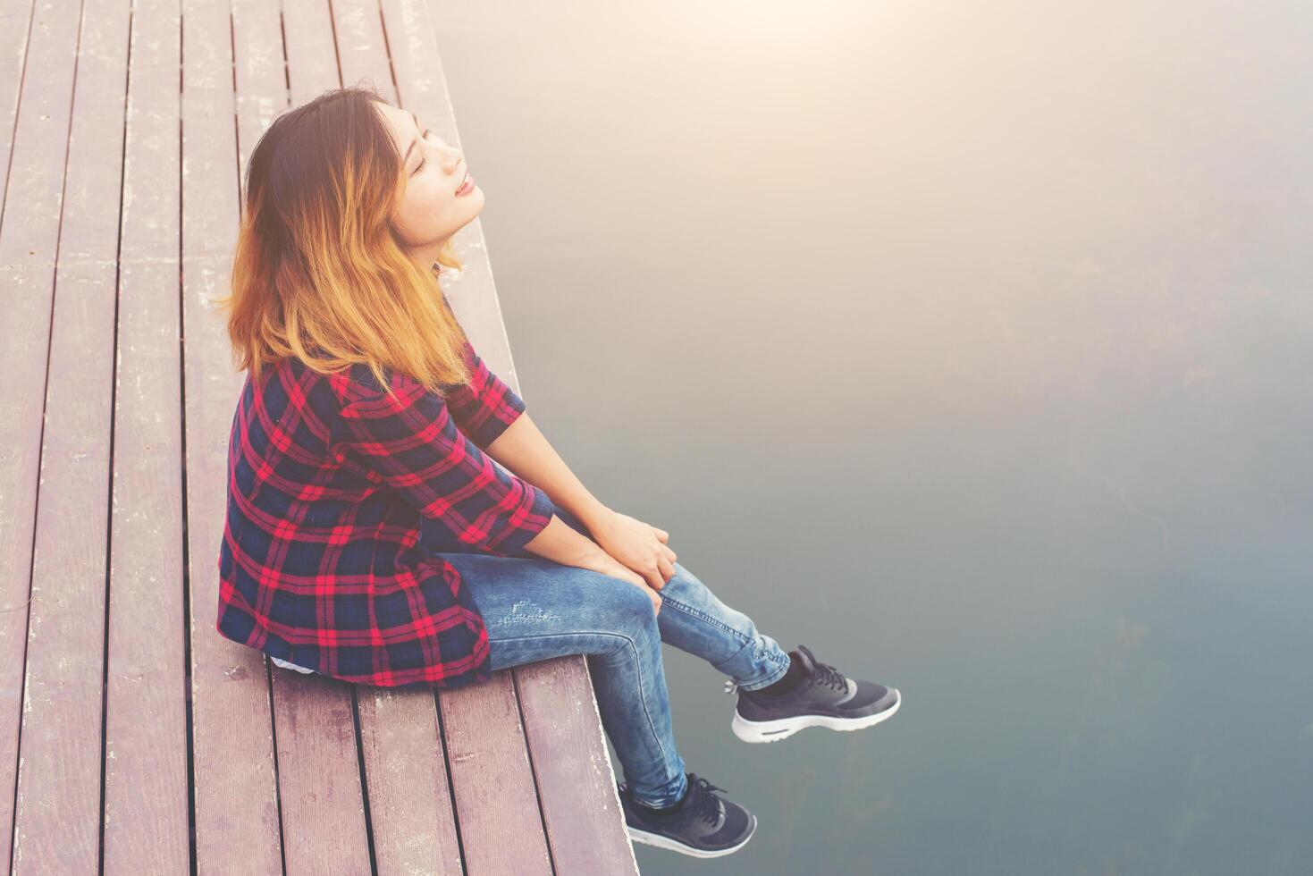 felice giovane donna hipster seduta al molo lago, rilassante godere con la natura. foto