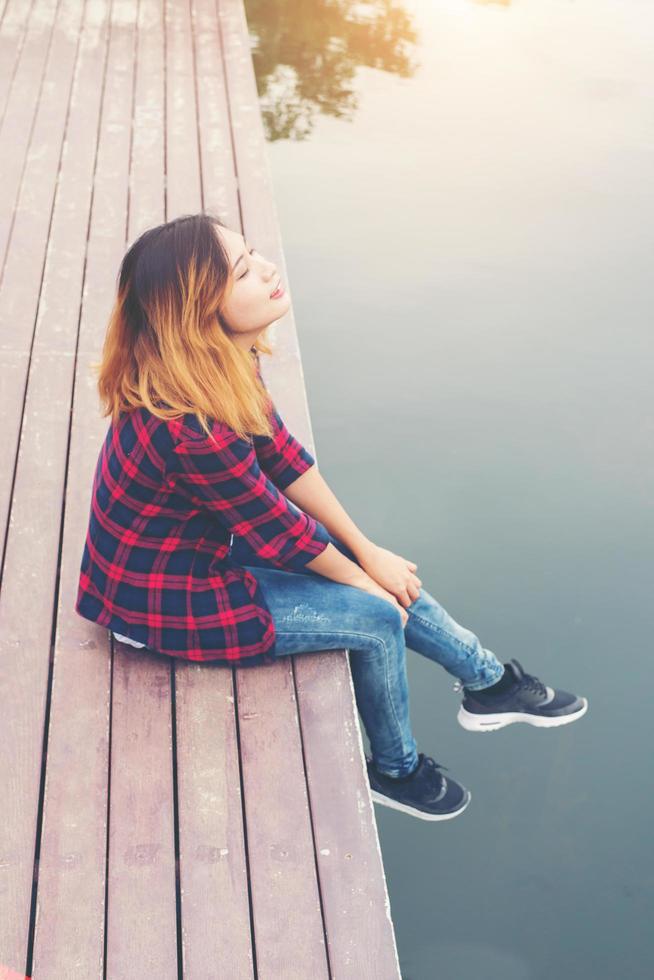 felice giovane donna hipster seduta al molo lago, rilassante godere con la natura. foto