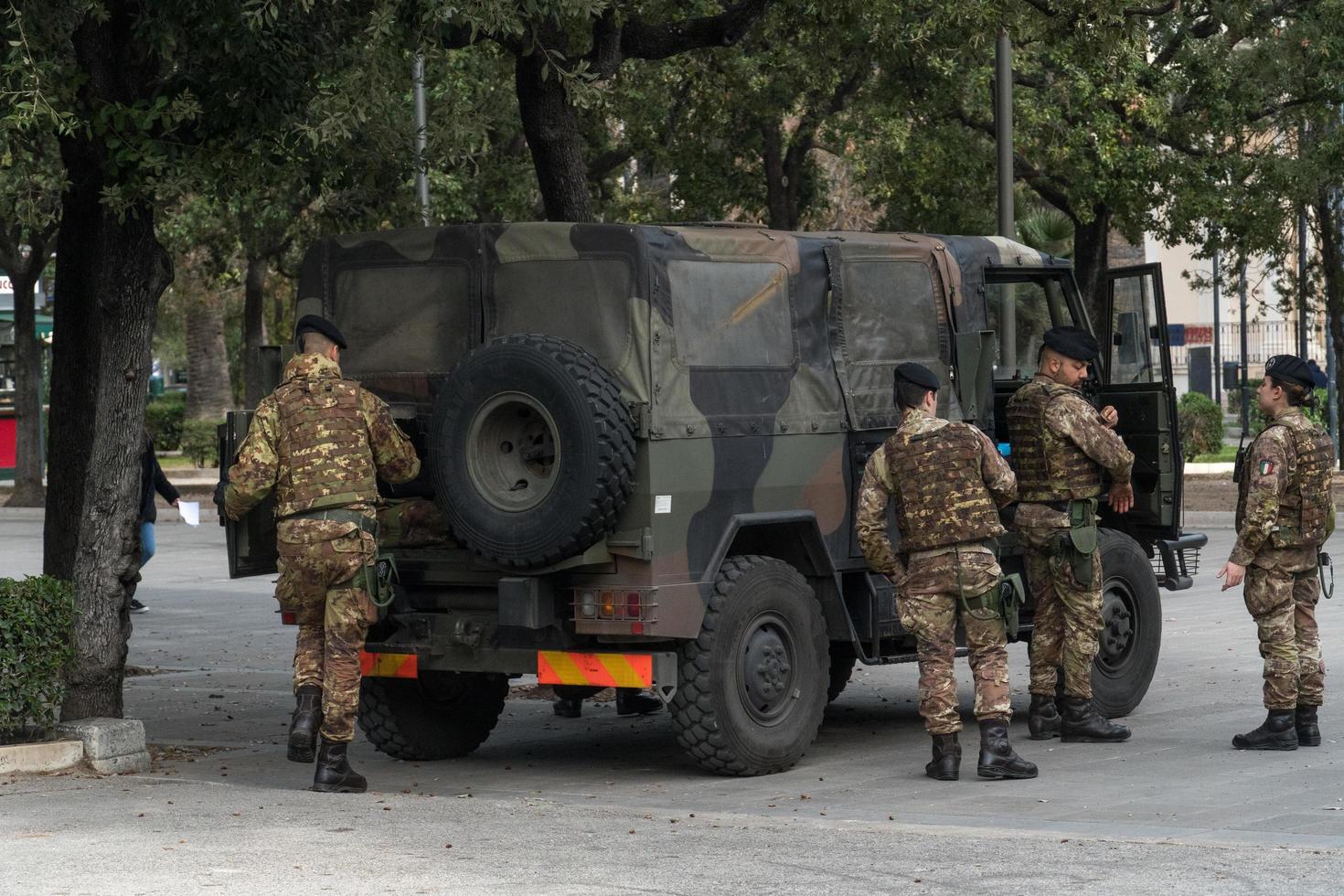 soldati italiani in mimetica in piedi accanto a un camion militare foto