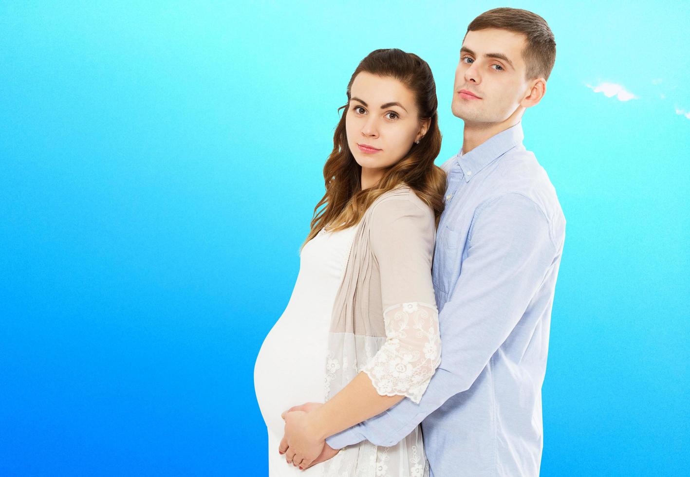 ritratto di giovane coppia in attesa del bambino isolato su sfondo blu, giovane coppia attraente madre incinta e padre felice, bella giovane coppia in attesa di bambino foto