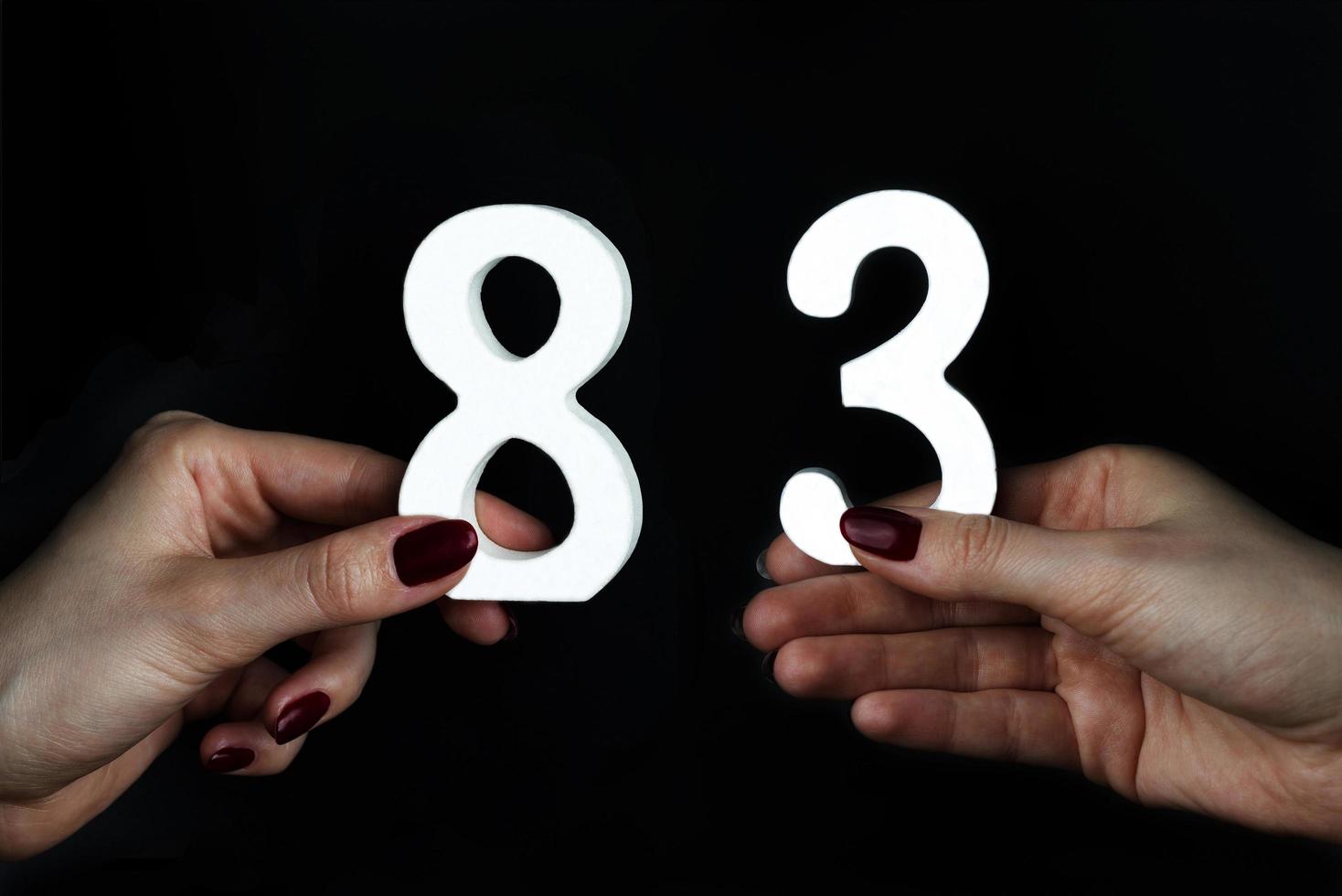 mani femminili che tengono i numeri ottantatre. foto