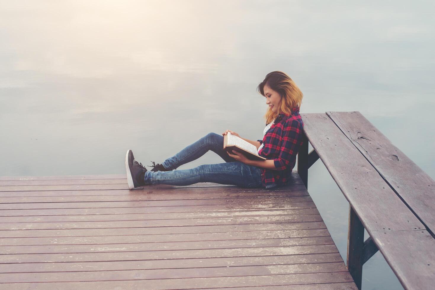 giovane bella donna hipster rilassante seduta sul molo libro di lettura. foto