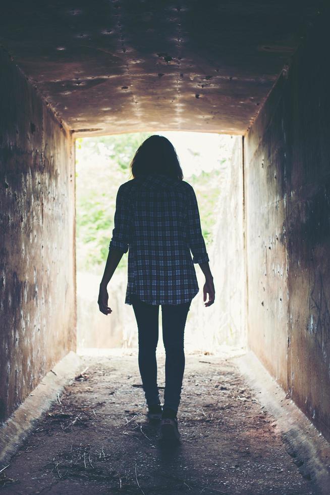 silhouette di donna hipster a piedi nel tunnel. luce alla fine del tunnel foto