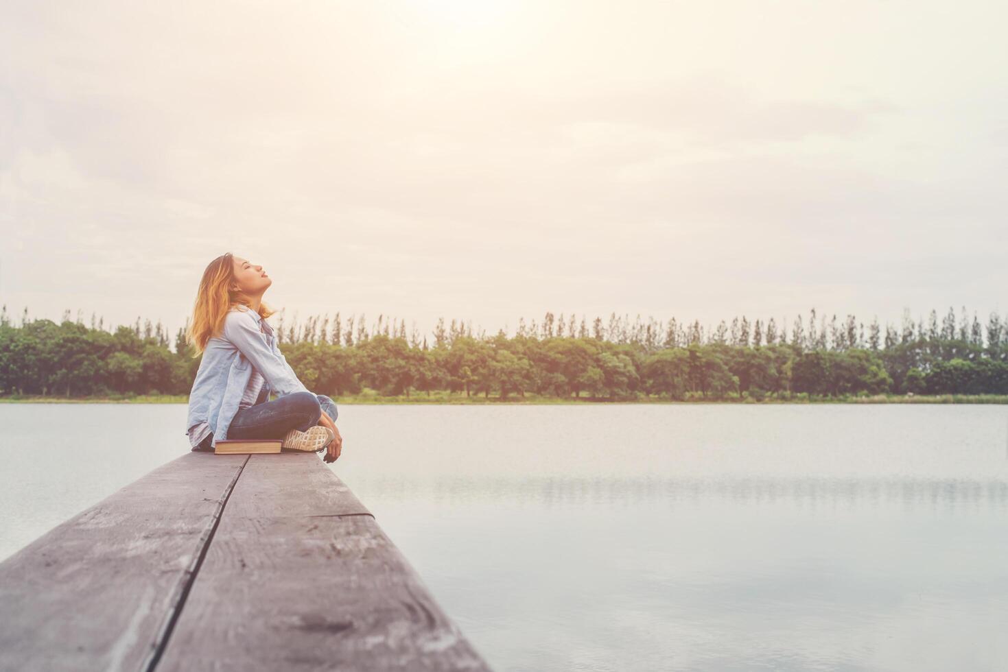 giovane bella donna hipster seduta sul lago rilassante con aria fresca. foto