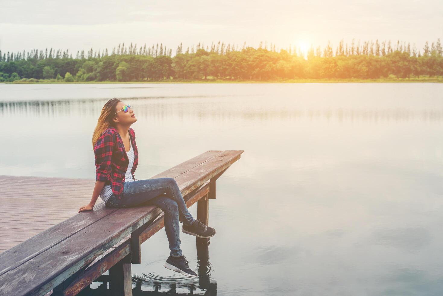 giovane bella donna hipster seduta sul molo del lago, atmosfera rilassata, estate. foto