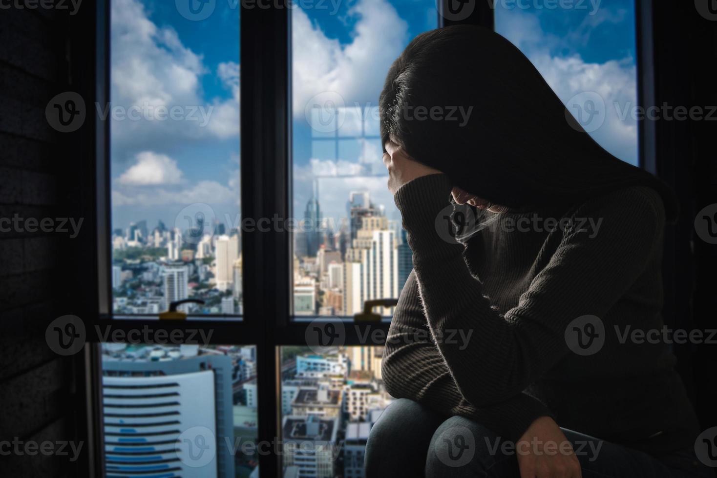 la donna si siede depressione in piedi vicino alla finestra e ansia foto