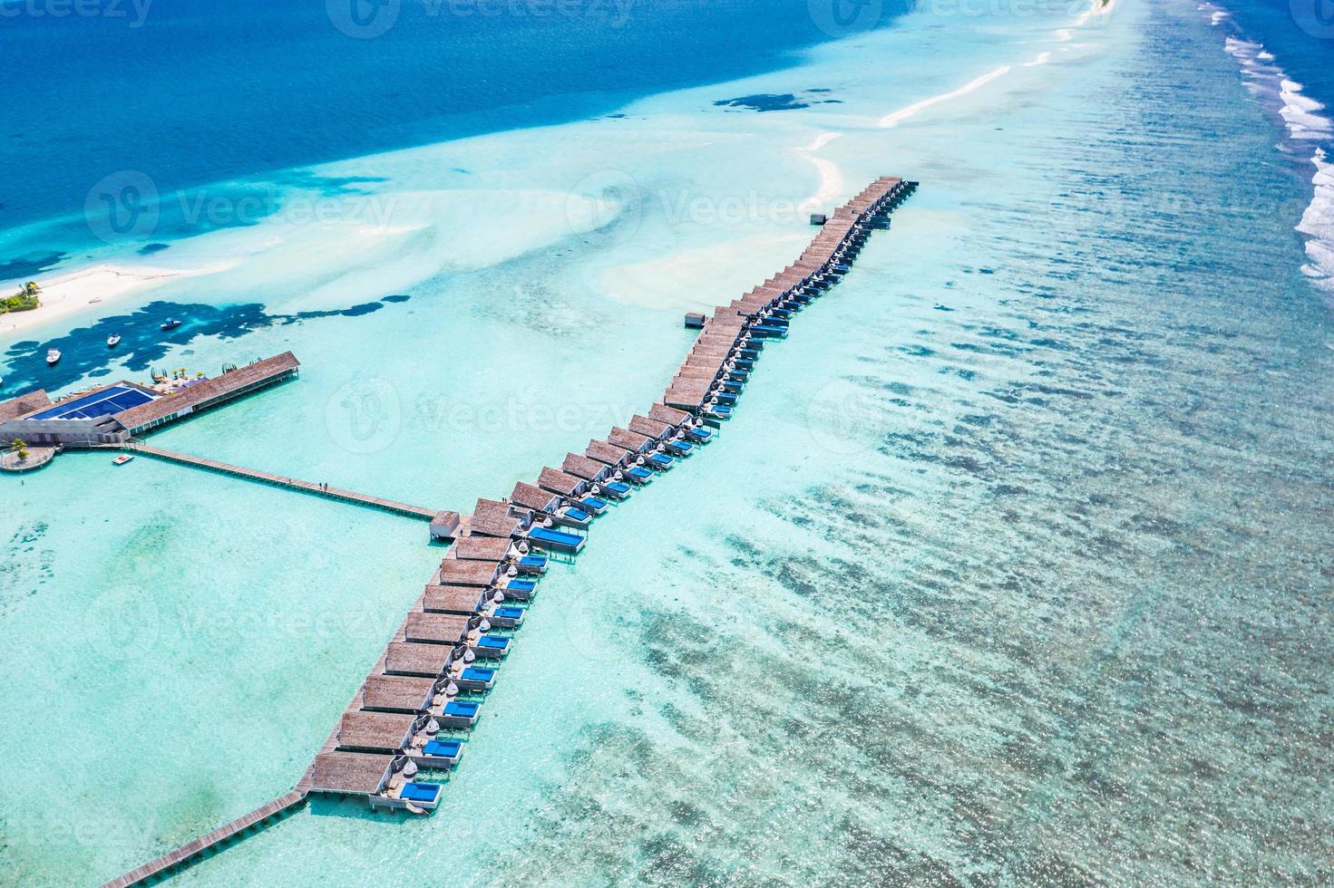 scenario paradisiaco delle maldive. paesaggio aereo tropicale, paesaggio marino con lungo molo, ville sull'acqua con splendida spiaggia di mare e laguna, natura tropicale. banner di destinazione turistica esotica, vacanze estive foto
