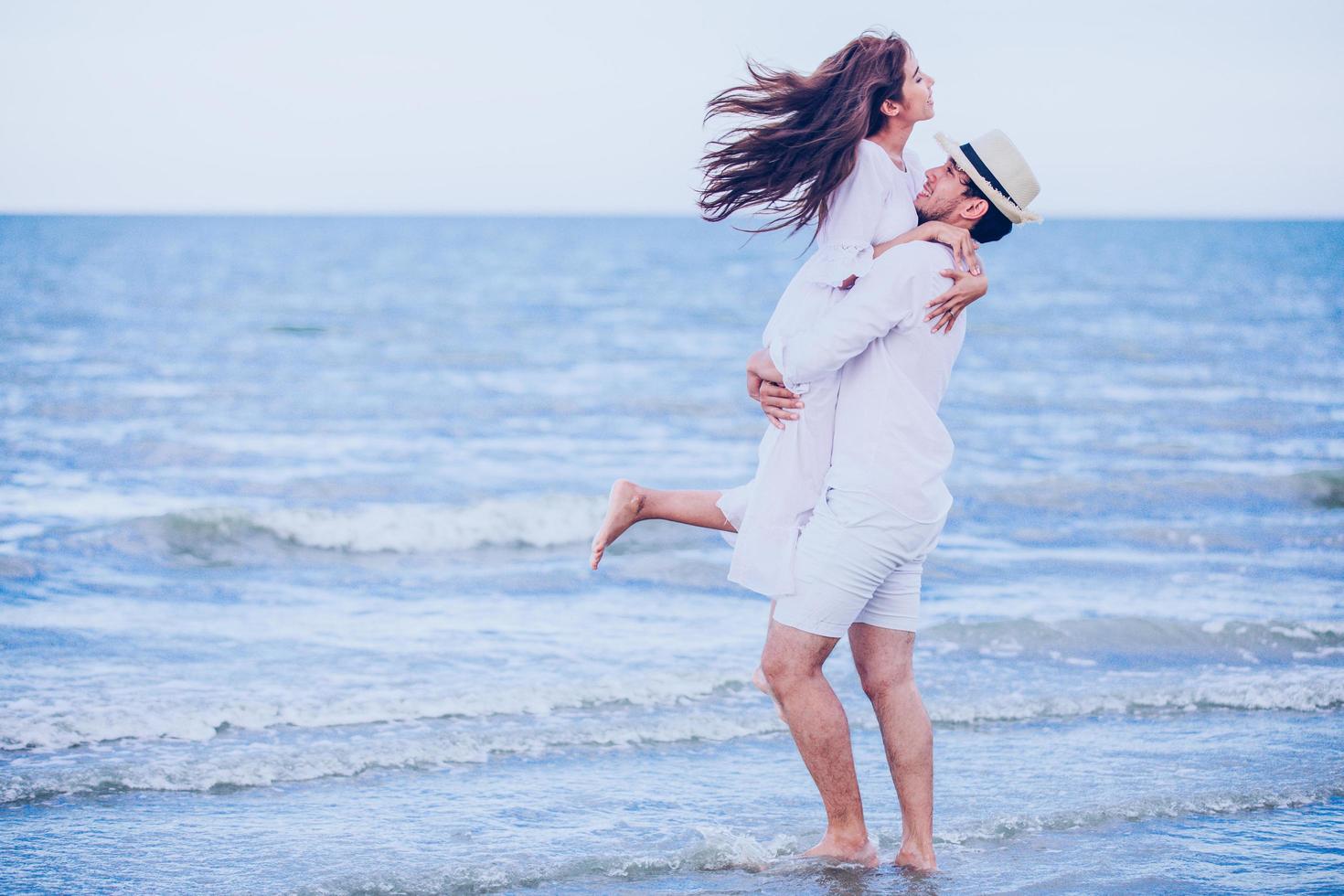 felice coppie romantiche amante che si tengono per mano insieme camminando sulla spiaggia foto