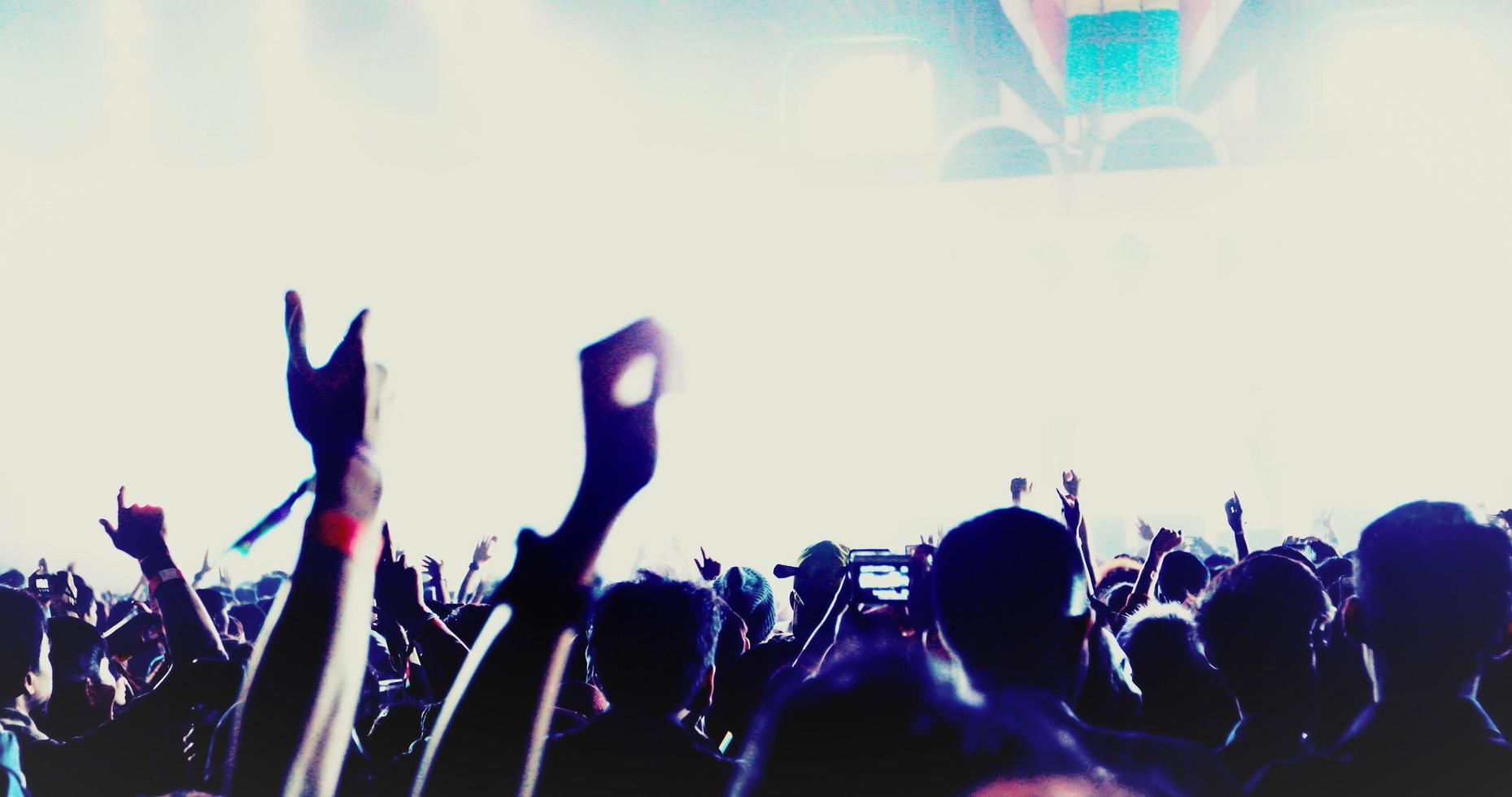 sagome della folla del concerto nella vista posteriore della folla del festival che alza le mani su luci di scena luminose foto