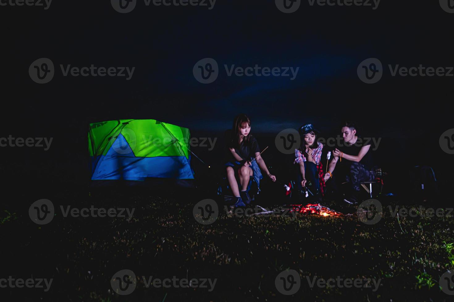 un gruppo di turisti asiatici che bevono e suonano la chitarra insieme alla felicità in estate mentre si accampano vicino al lago foto