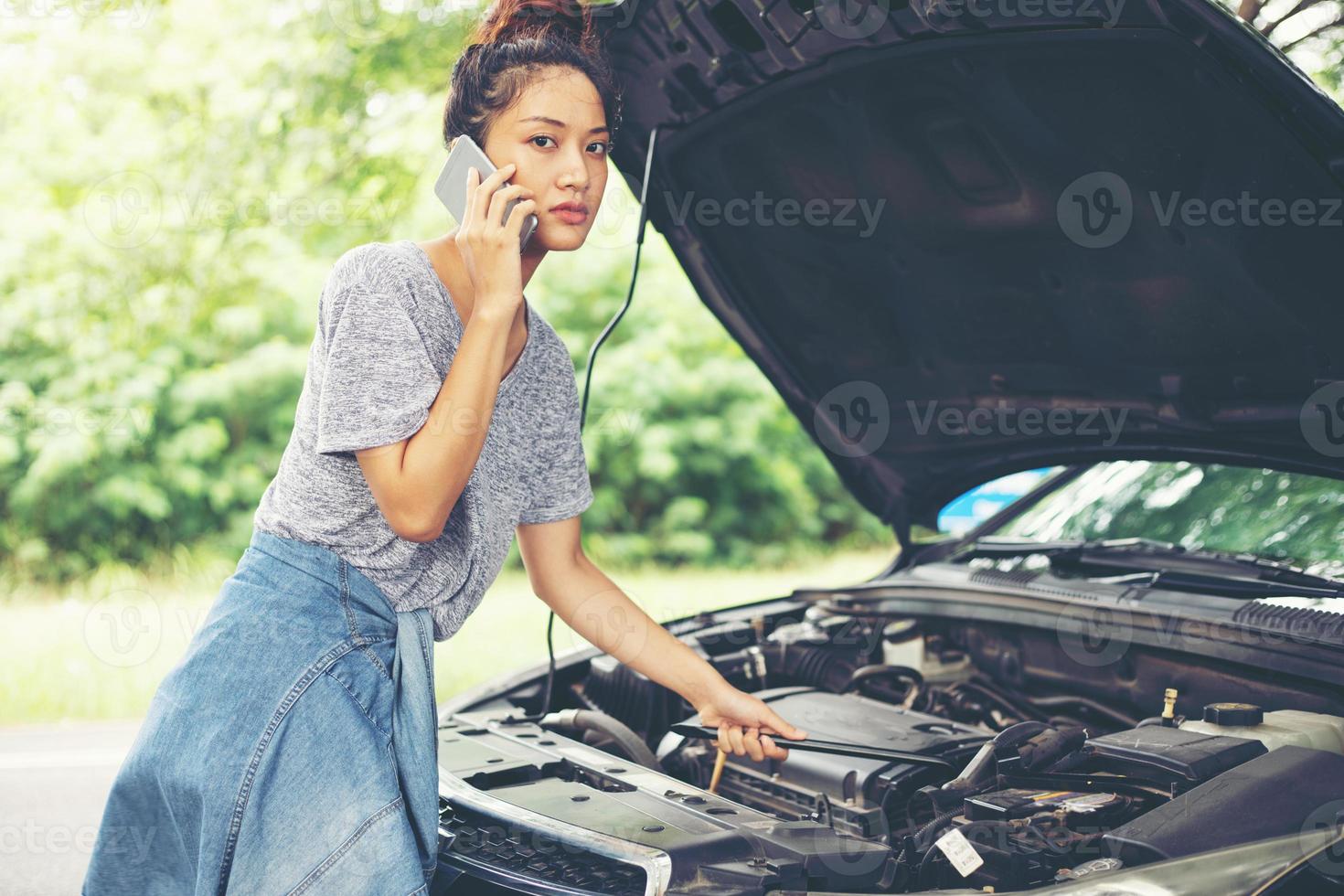 messa a fuoco sfocata e morbida di una donna asiatica che usa il telefono cellulare mentre guarda e stressa l'uomo seduto dopo un guasto alla macchina per strada foto