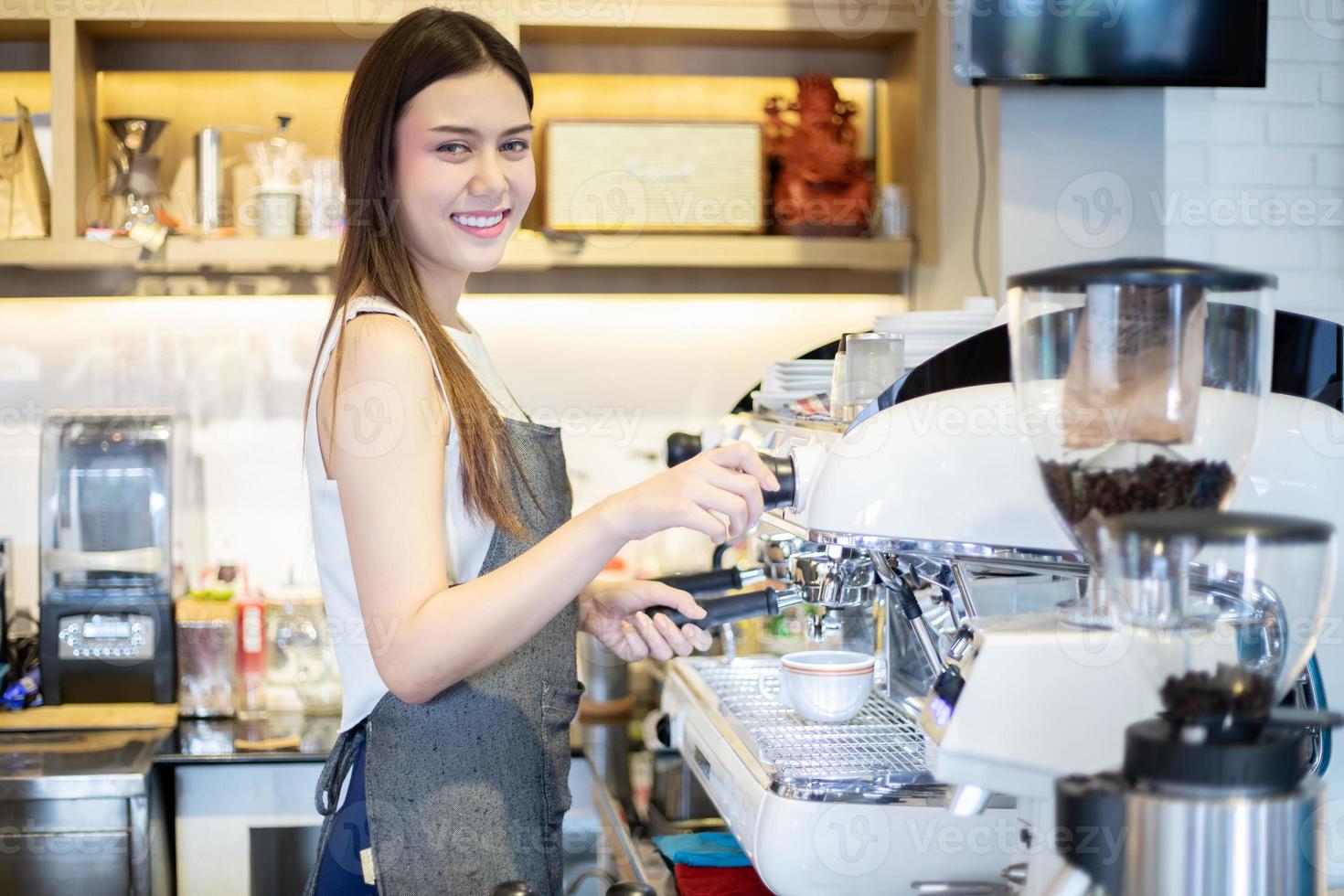 barista delle donne asiatiche che sorride e usa la macchina da caffè nel bancone della caffetteria - donna che lavora proprietario di una piccola impresa cibo e bevande concetto di caffè foto