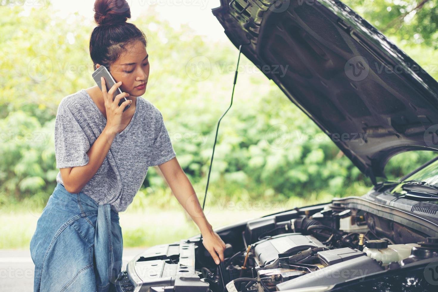 messa a fuoco sfocata e morbida di una donna asiatica che usa il telefono cellulare mentre guarda e stressa l'uomo seduto dopo un guasto alla macchina per strada foto