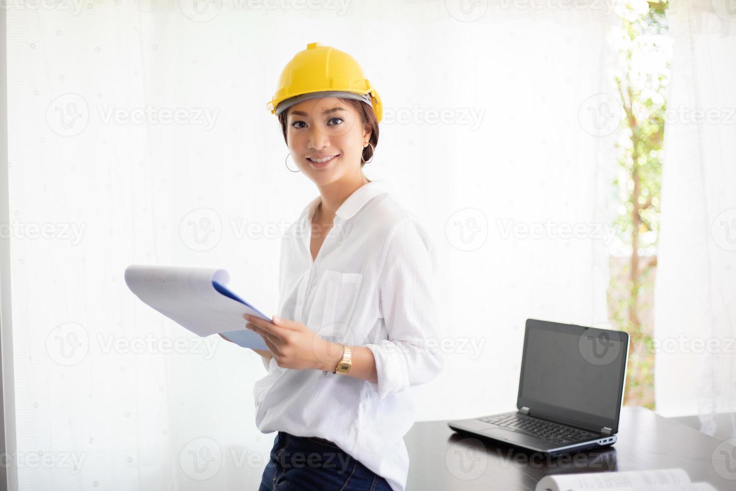 donne asiatiche che ingegnerizzano, ispezionano e lavorano e tengono progetti in ufficio. sta sorridendo felice per il lavoro foto