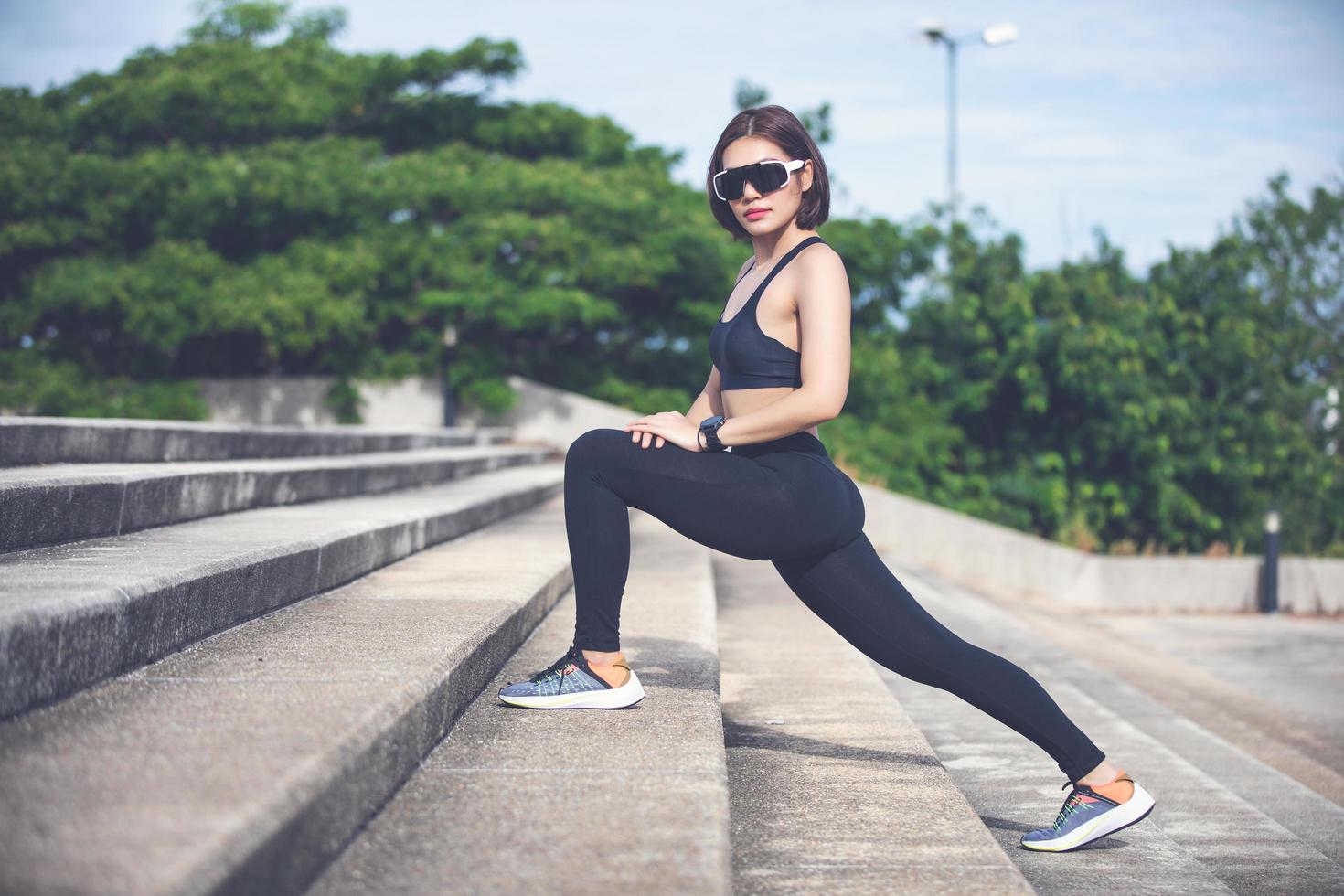 donna atletica riscaldamento asiatico e giovane atleta femminile seduto su un esercizio e stretching in un parco prima del corridore all'aperto, concetto di stile di vita sano foto