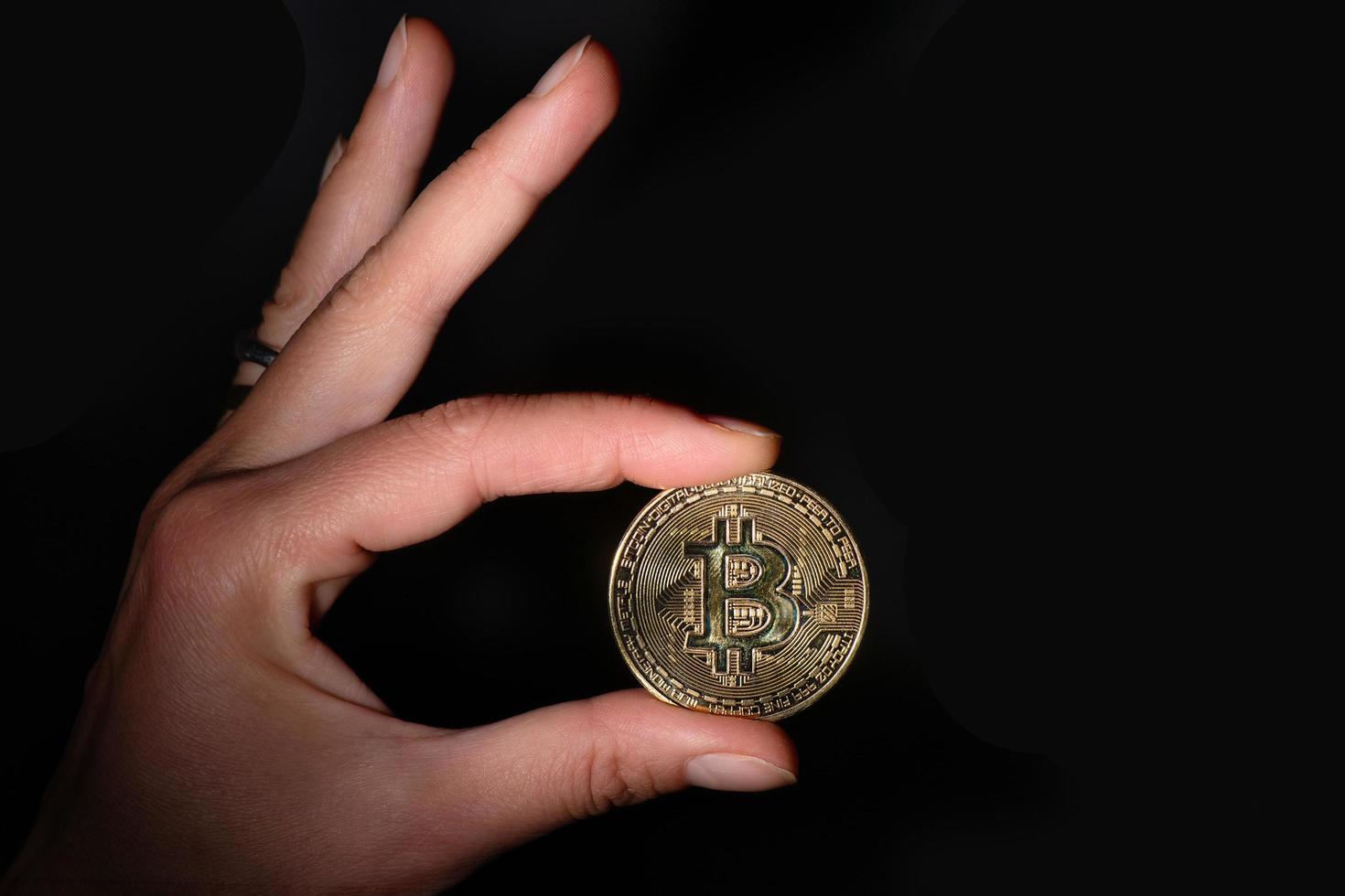 moneta di criptovaluta tenuta tra le dita foto