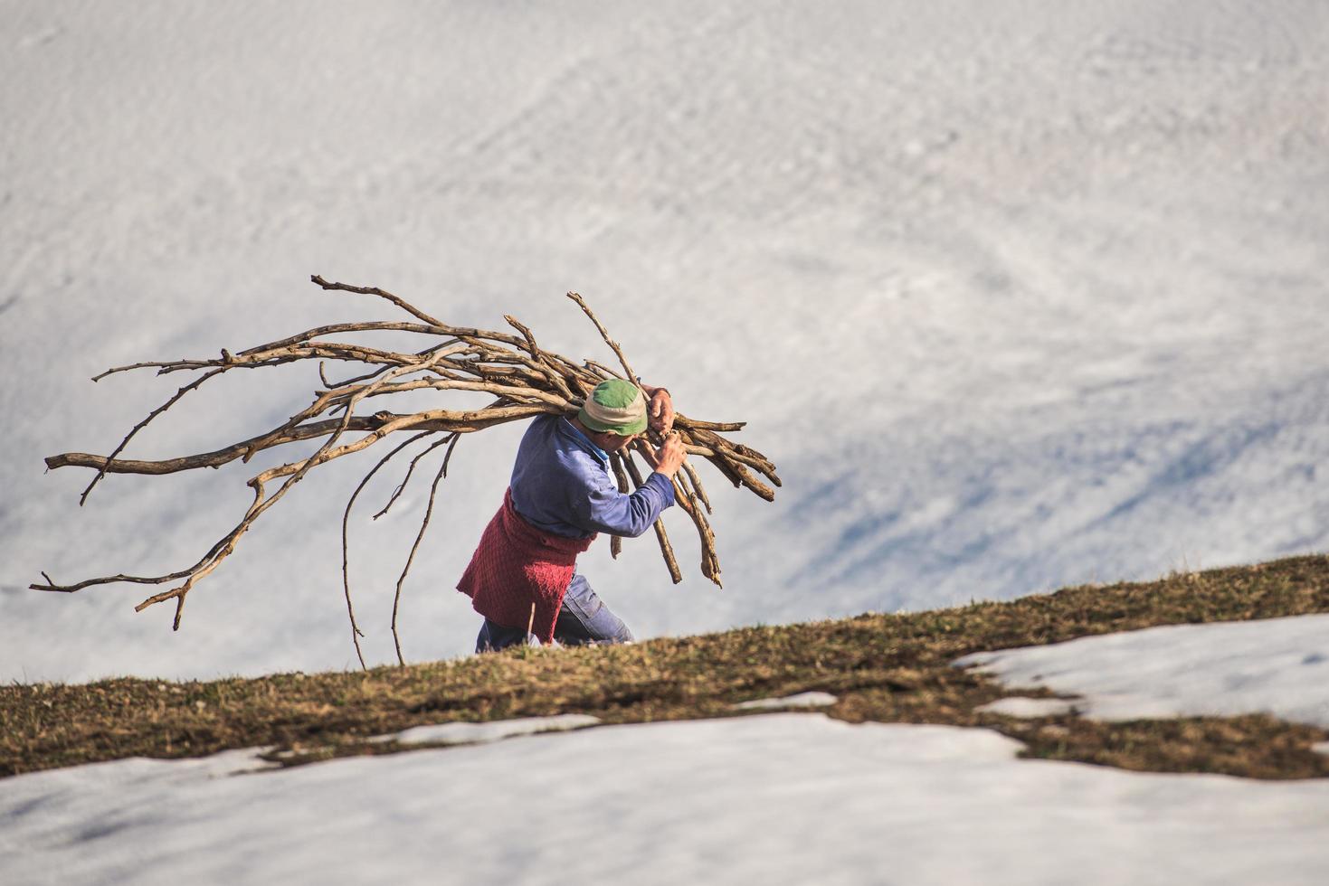 l'uomo porta legna da ardere verso casa in un luogo rurale nella neve foto