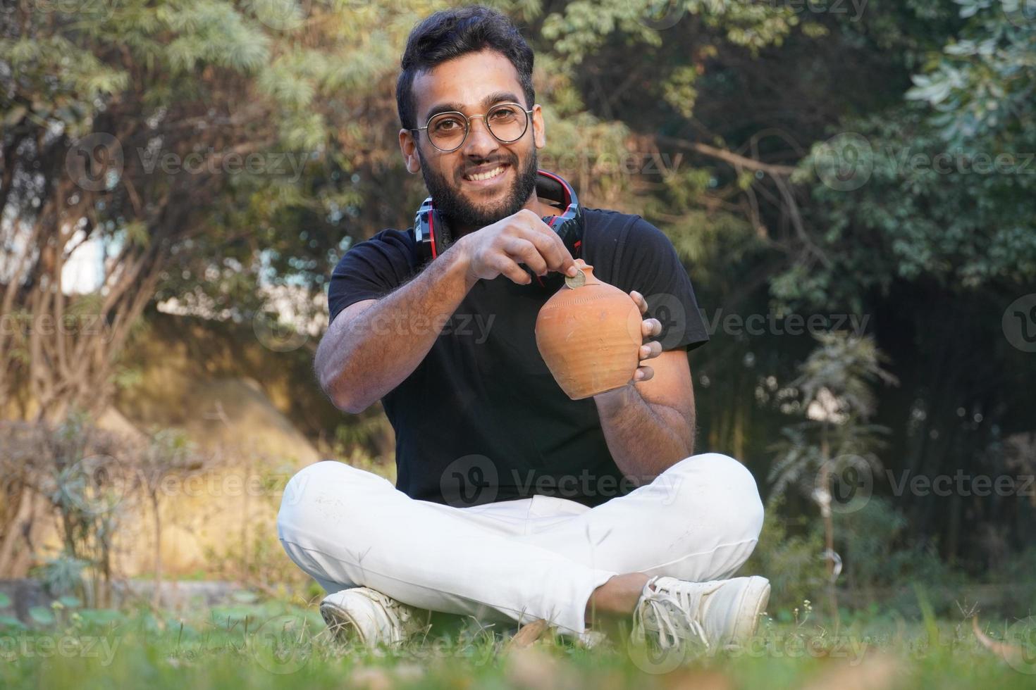 un uomo tiene un auricolare sulla spalla e deposita i soldi sul suo salvadanaio foto