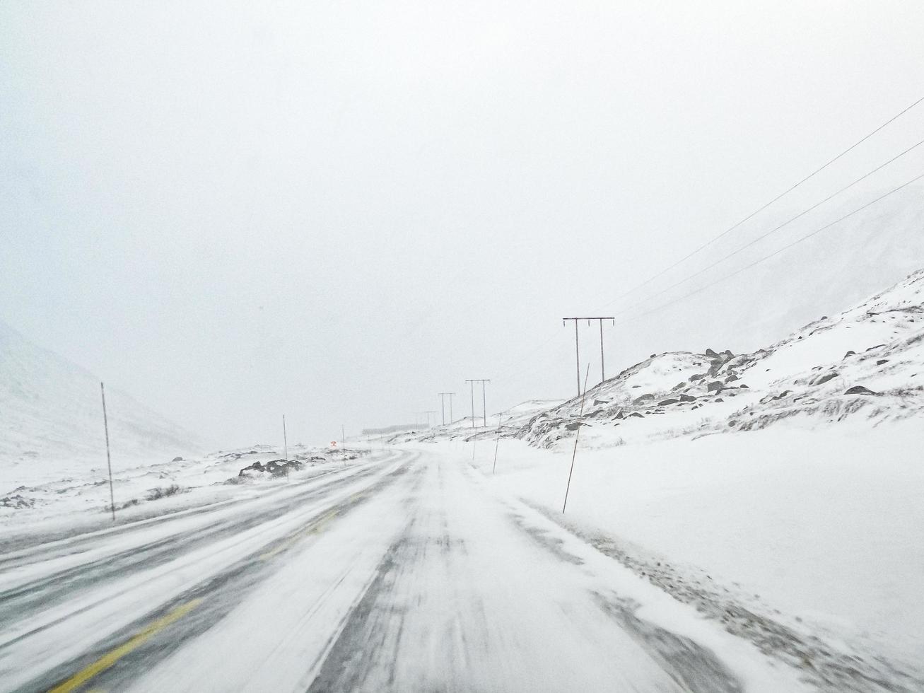 guidando attraverso la tempesta di neve di blizzard con ghiaccio nero sulla strada, norvegia. foto