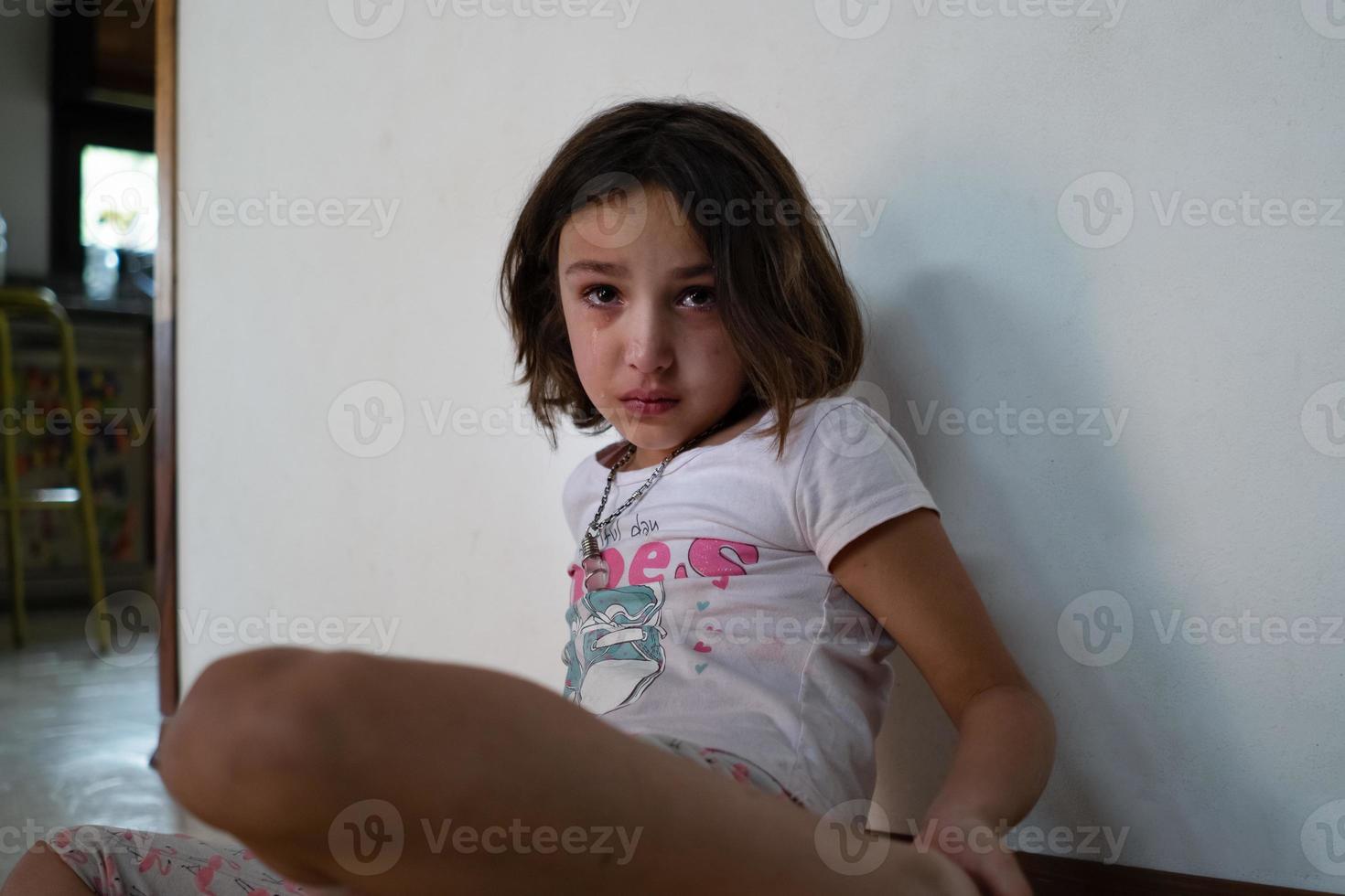 ragazza che piange seduta sul pavimento a casa. foto