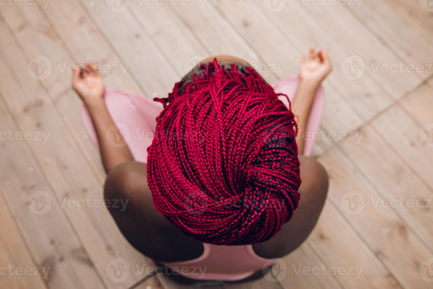 primo piano delle trecce rosse di una donna che fa meditazione foto