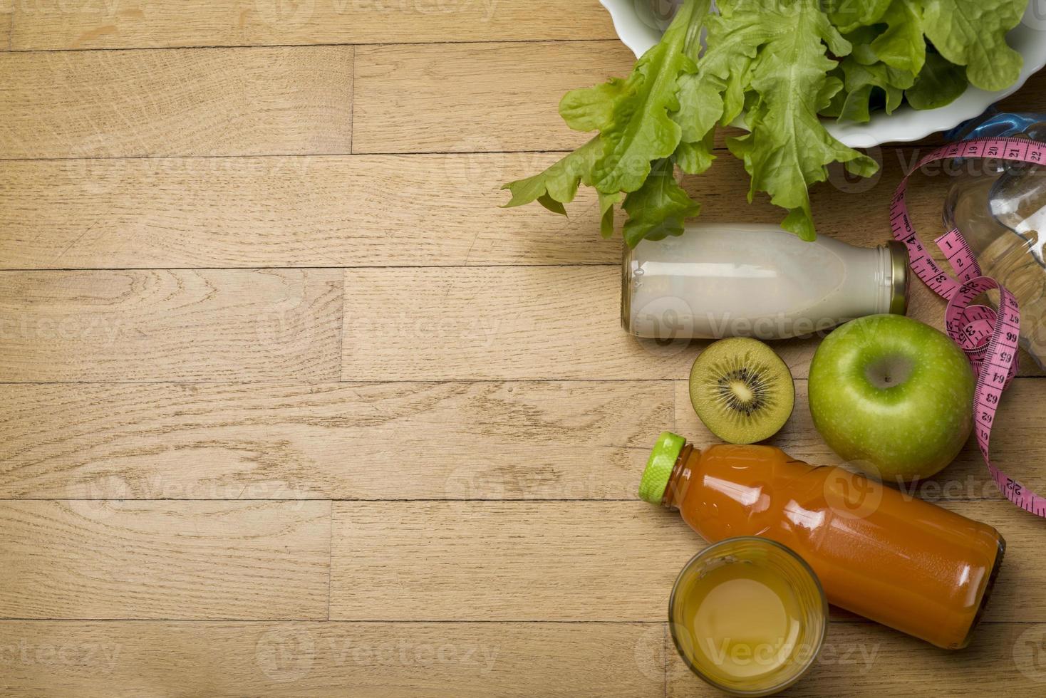 programma di dieta, metro a nastro, acqua, dieta di frutta fresca sul pavimento di legno. foto