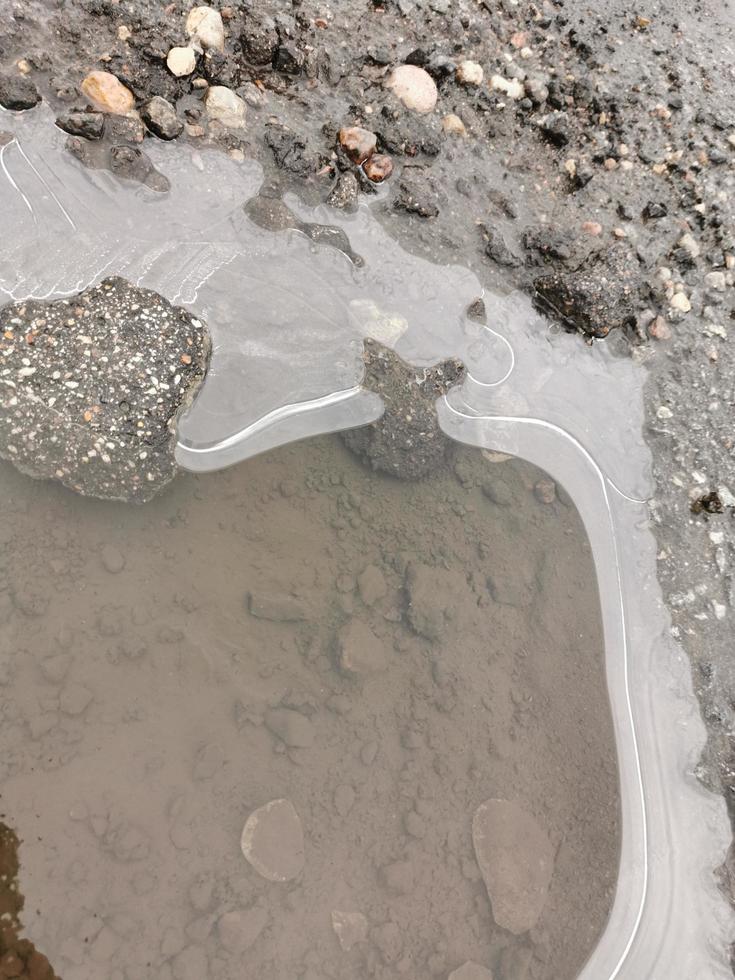 pozzanghera congelata sul marciapiede. il ghiaccio si è congelato in cerchi foto