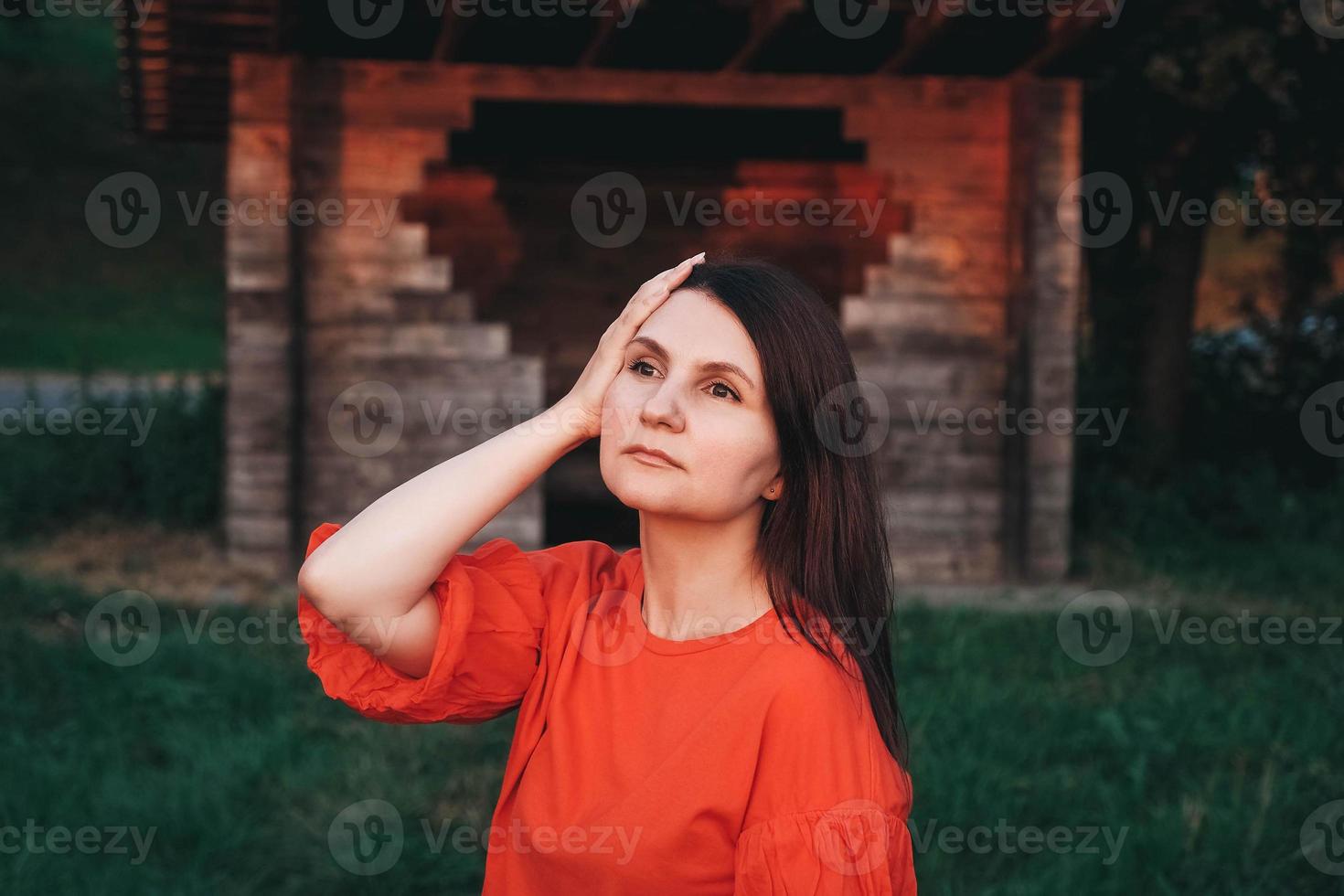 bella donna vestita di rosso si erge sullo sfondo di una casa di legno foto