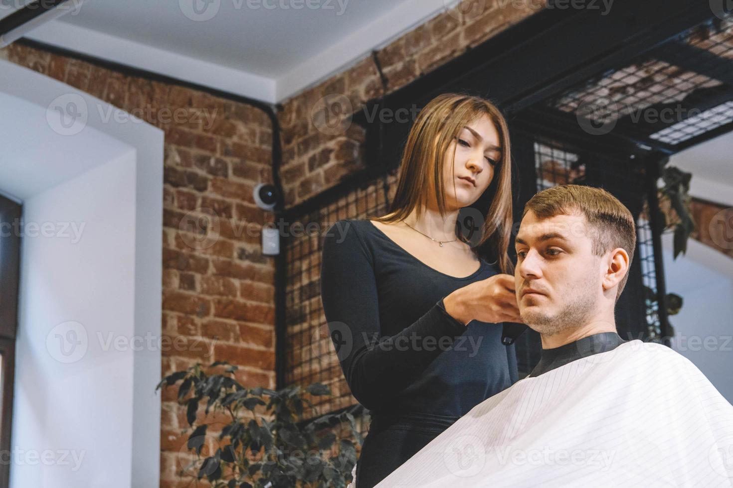 bella donna parrucchiere che taglia i capelli del cliente con le forbici in un negozio di barbiere. concetto di pubblicità e parrucchiere foto
