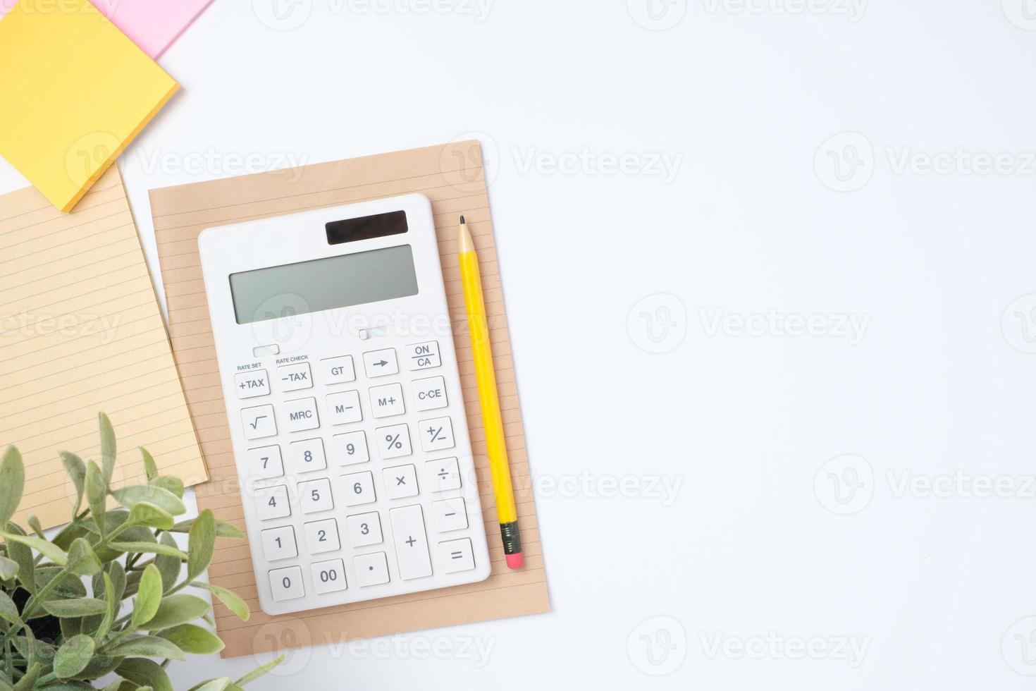 scrivania vista dall'alto con calcolatrice e taccuino su sfondo bianco tavolo foto