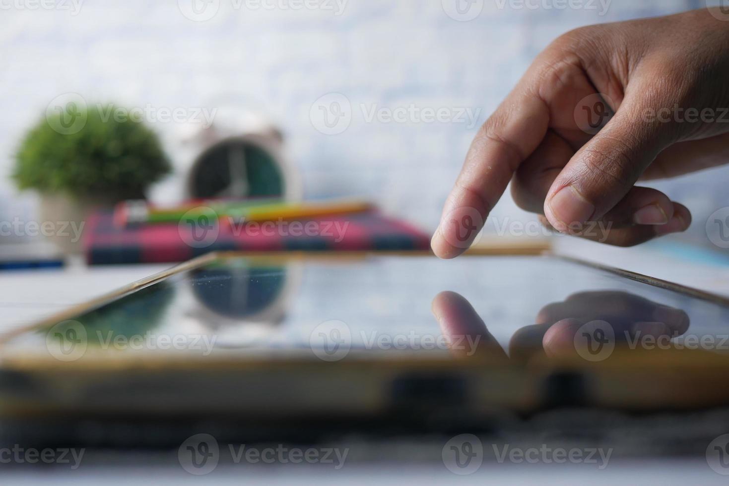 mano del bambino che punta il dito sullo schermo della tavoletta digitale. foto