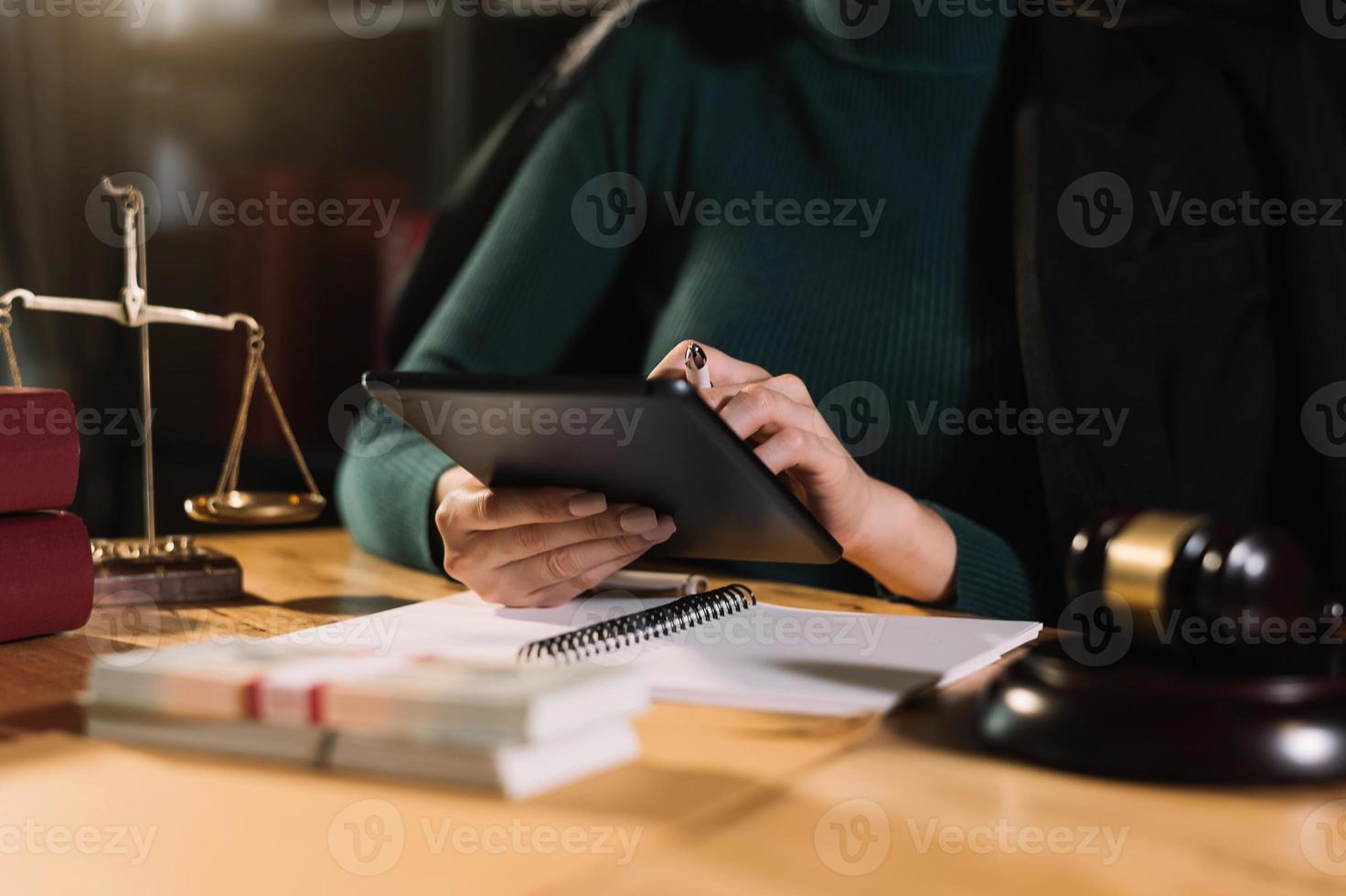 concetto di giustizia e diritto. giudice maschio in un'aula di tribunale con il martelletto, lavorando con computer e tastiera docking, occhiali, sul tavolo foto