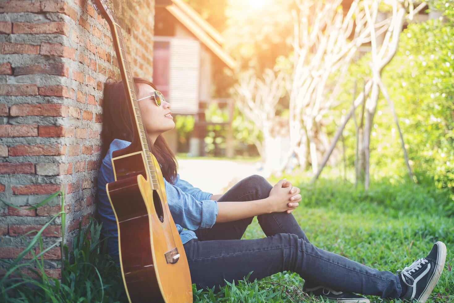 giovane ragazza hipster seduta a suonare una chitarra e cantare. foto