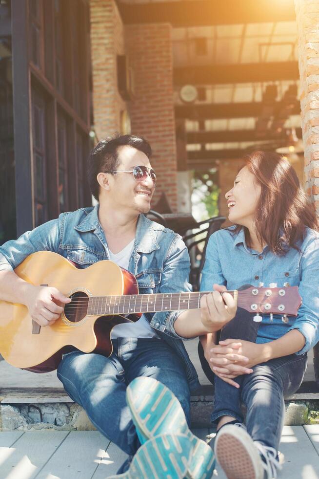 coppia hipster seduta rilassata con una bella atmosfera con il primo appuntamento si diverte a suonare la chitarra come un grande momento insieme. foto