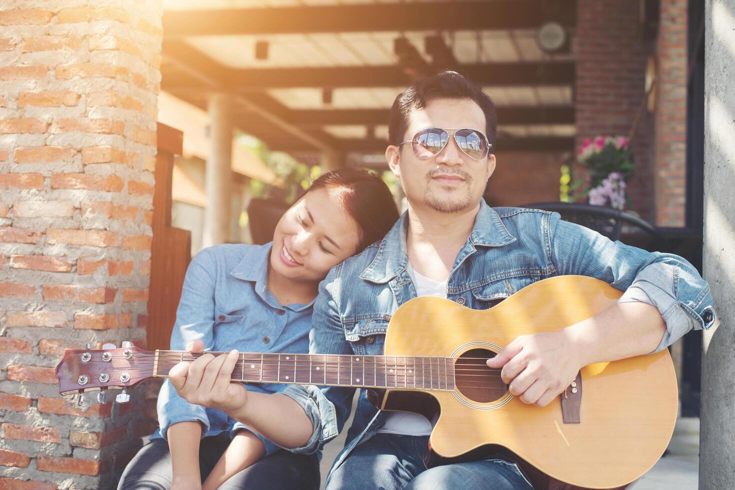 coppia hipster seduta rilassata con una bella atmosfera con il primo appuntamento si diverte a suonare la chitarra come un grande momento insieme. foto