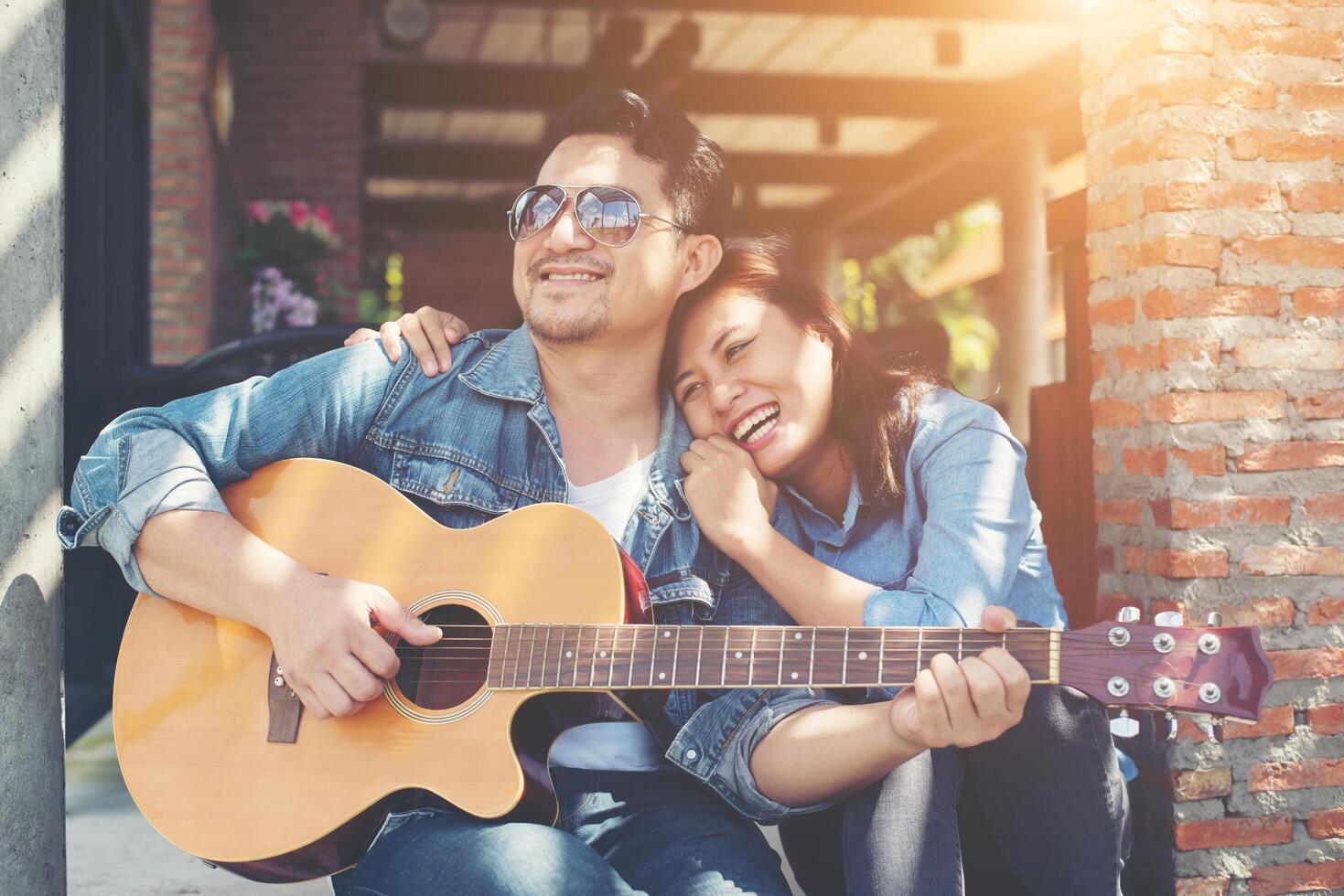 coppia hipster seduta rilassata con una bella atmosfera con il primo appuntamento si diverte a suonare la chitarra come un grande momento insieme. foto