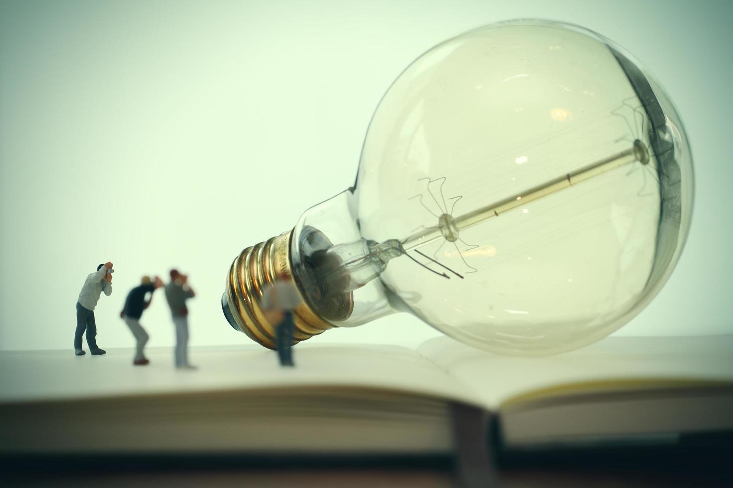 concetto di idea creativa - fotografo in miniatura con lampadina vintage su quaderno di carta aperto foto