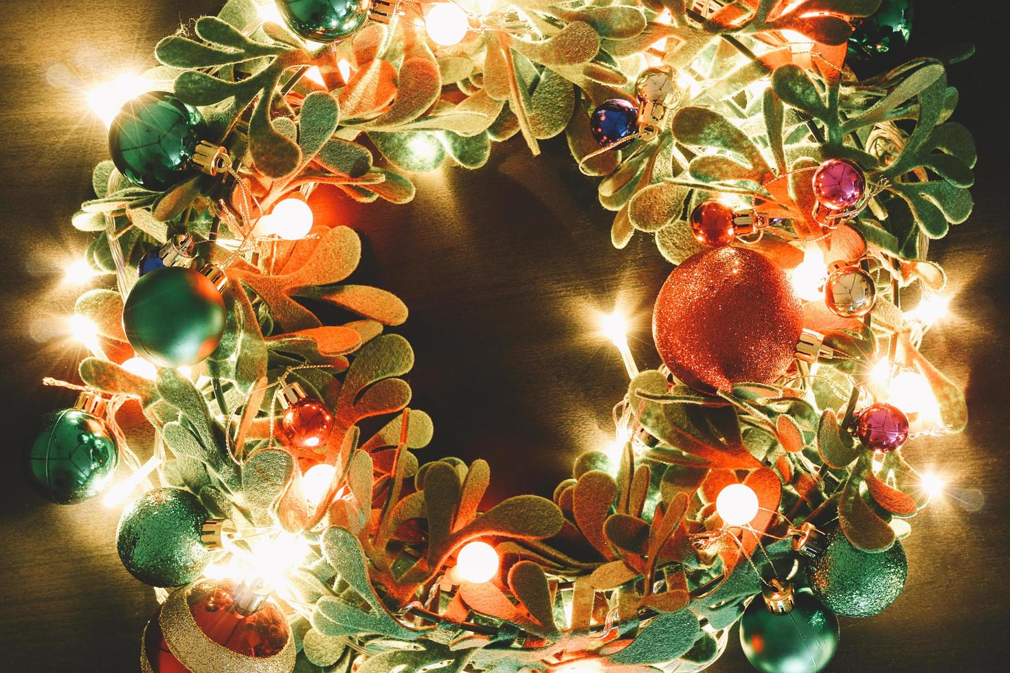 concetto di stagione di auguri. corona di Natale con luce decorativa su sfondo di legno scuro foto
