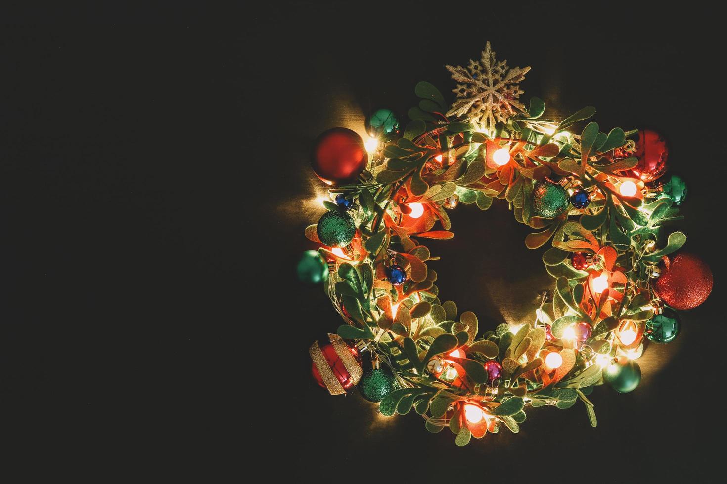 concetto di stagione di auguri. corona di Natale con luce decorativa su sfondo di legno scuro foto