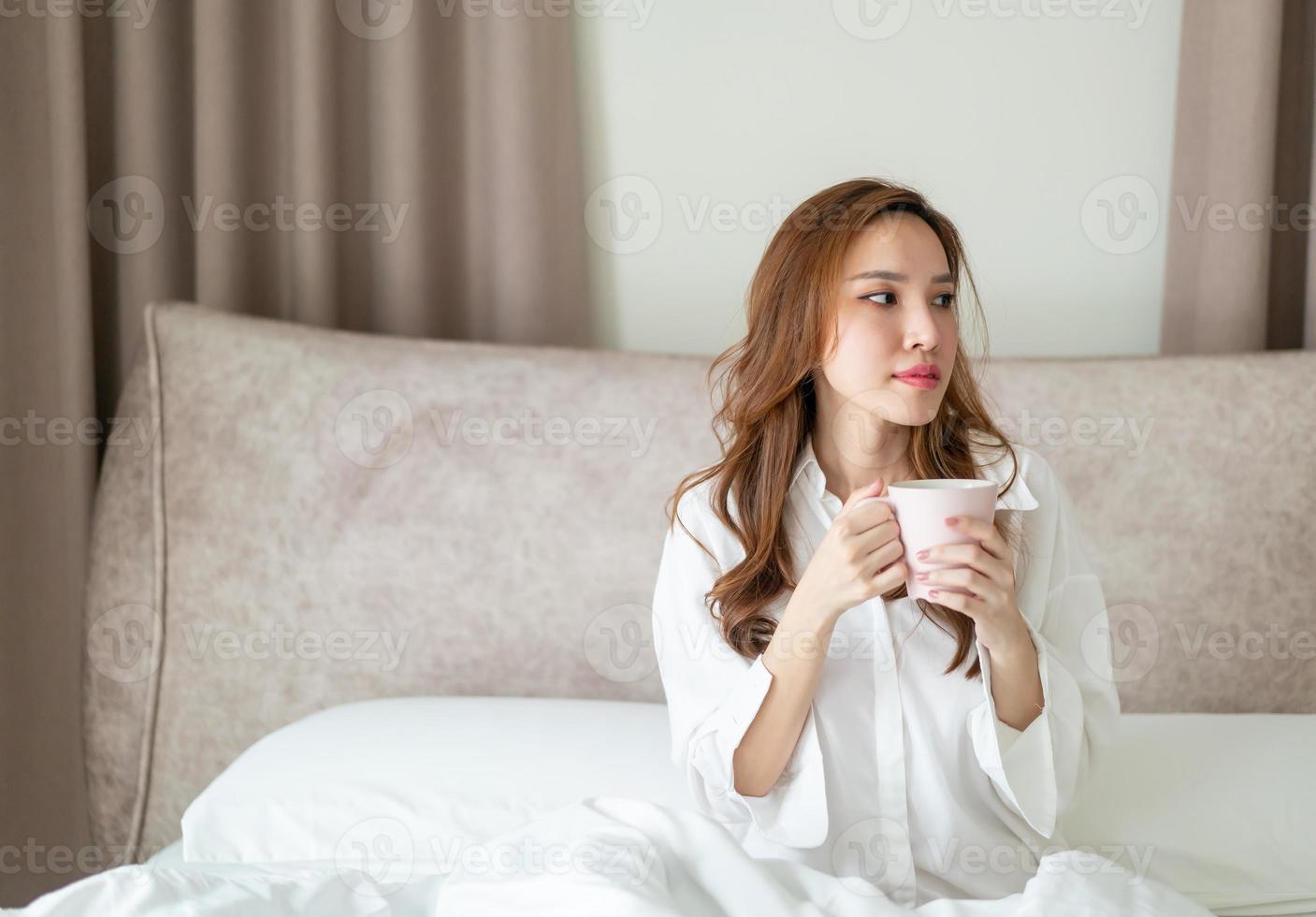 ritratto bella donna sveglia e tenendo tazza di caffè o tazza sul letto foto