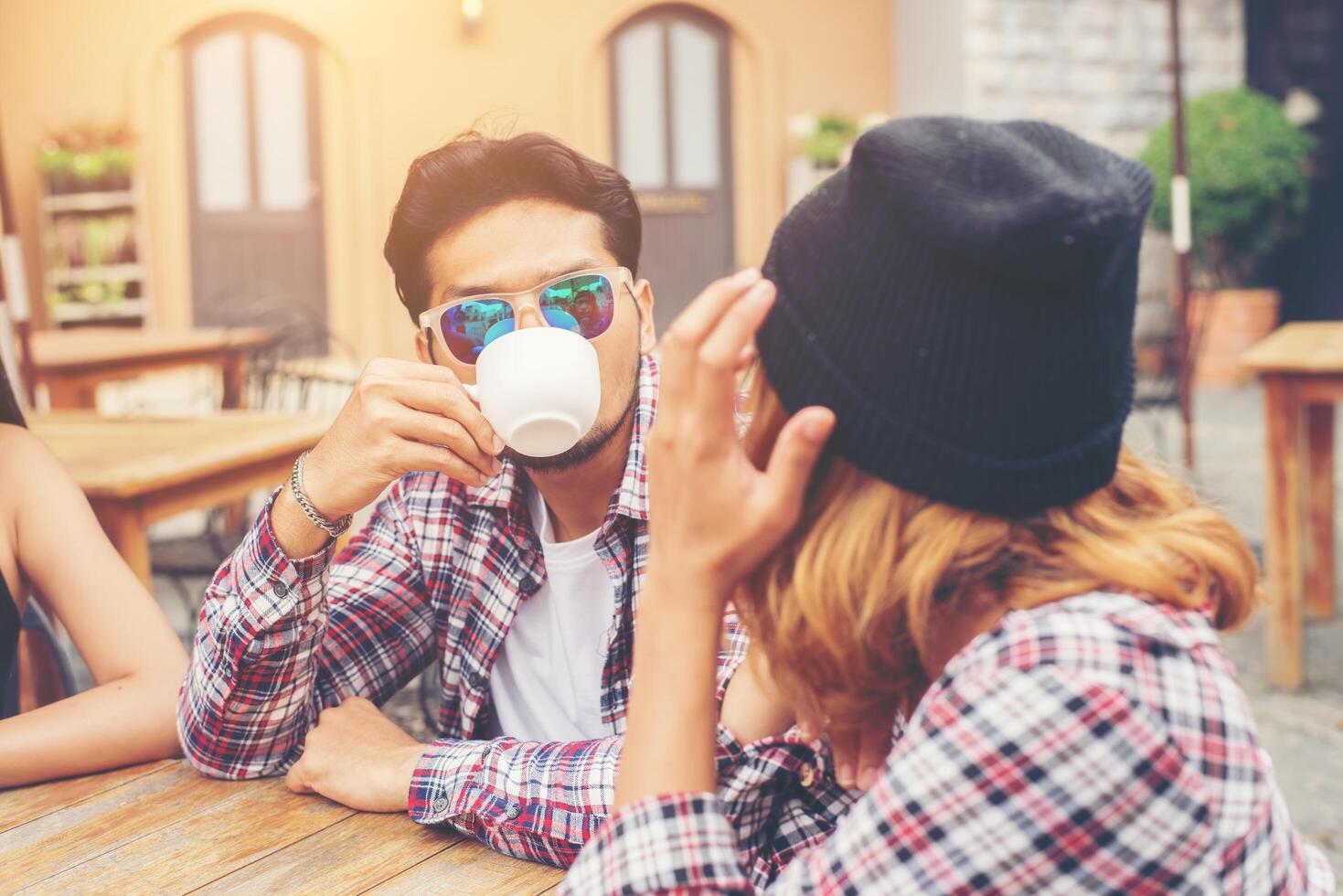 gruppo di giovani hipster seduti in un caffè, giovani amici allegri che si divertono mentre si prendono del tempo insieme, goditi la libertà delle vacanze. foto